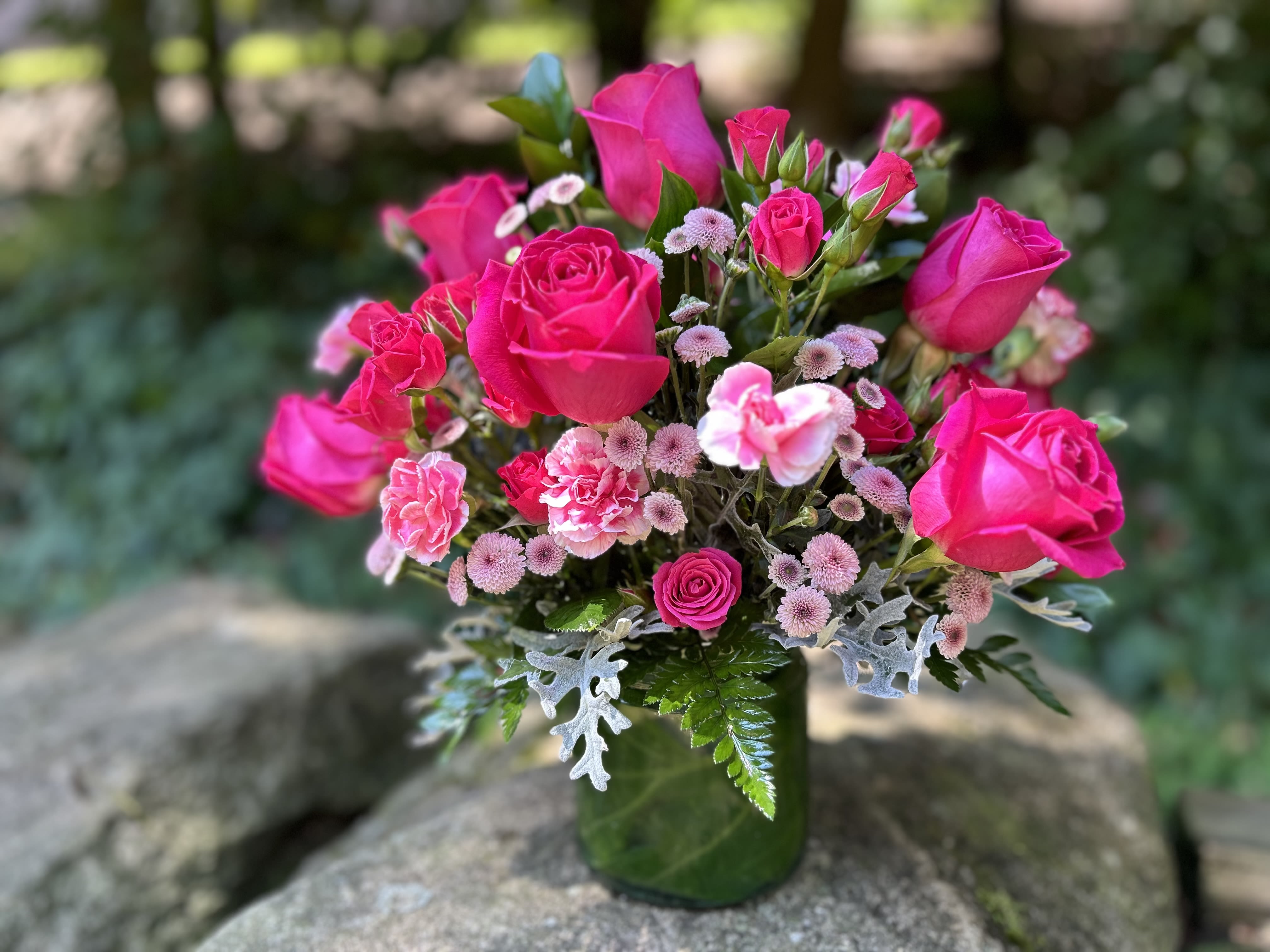 Pink Beauty - Hot pink roses and spray roses, pink pins and mini carnations styled in a glass vase with greenery.