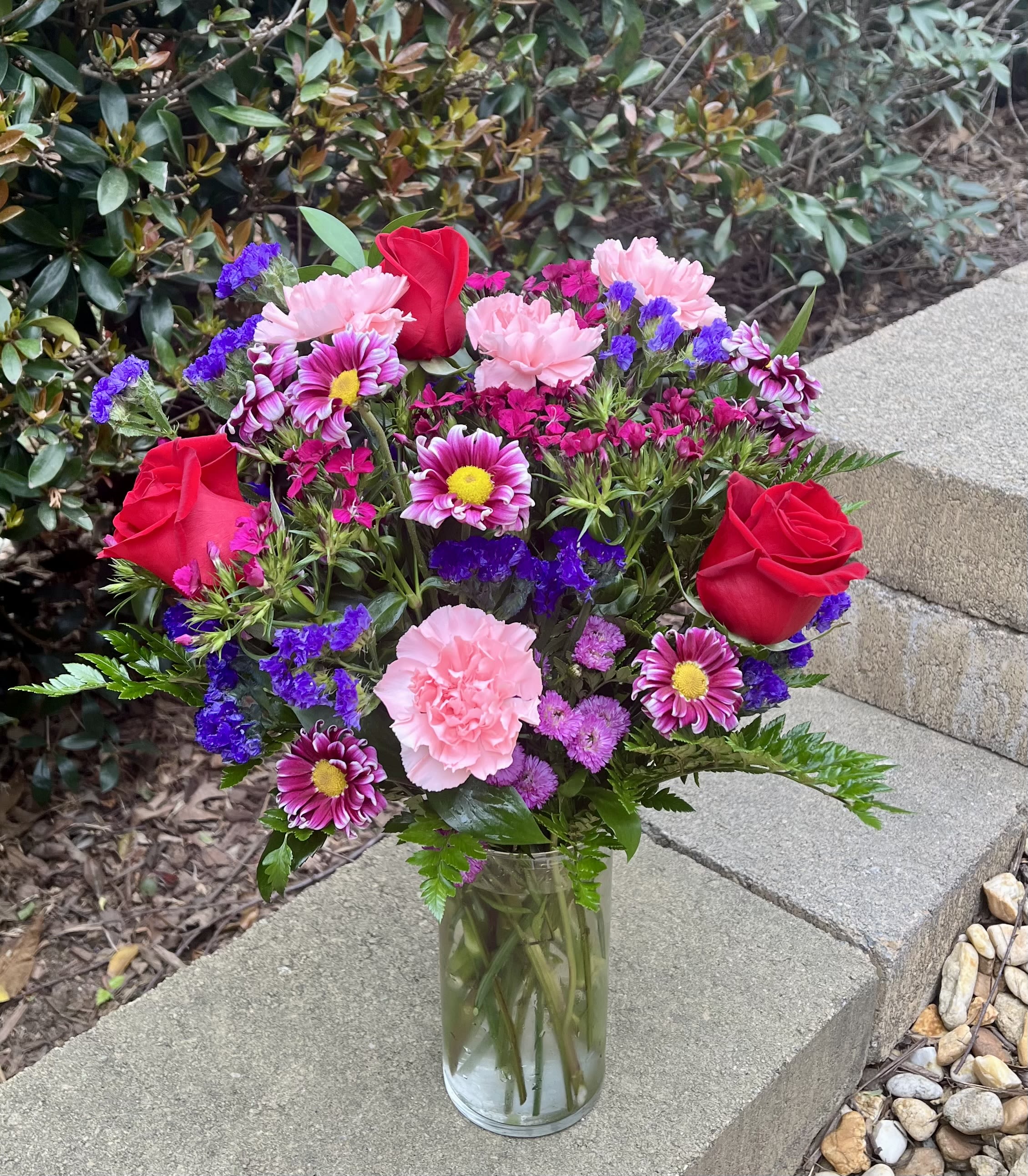 Radiant Joy - A bold colored arrangement of roses, daisies, carnations, and filler flowers arranged into a traditional bouquet.