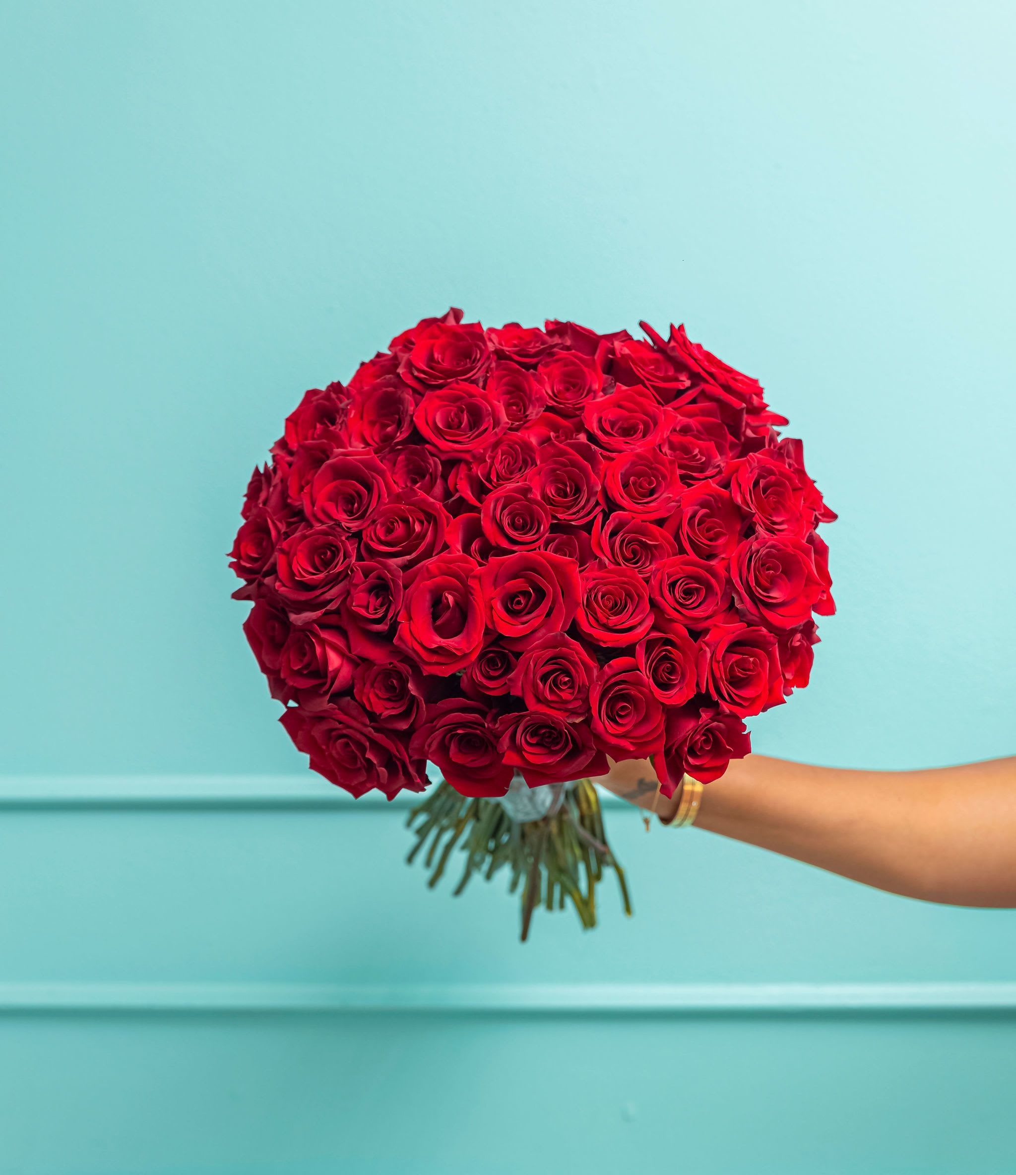 The Renee Red - Indulge in the timeless beauty of roses with our “Renee” Collection All Rose Cluster Bouquet. Each bundle of premium blooms is meticulously hand-tied to showcase the lush vibrancy and elegance of every stem. Whether you’re marking a milestone, expressing heartfelt gratitude, or simply brightening someone’s day, this classic bouquet delivers a message of romance and sophistication.  Key Features Available in Standard (25 stems), Deluxe (50 stems), or Premium (100 stems) to suit any occasion—from a modest gesture to an extravagant display. Premium Quality Roses are chosen for their rich color and long-lasting freshness. Hand-Tied Presentation finished with a coordinating ribbon, creating a stunning visual impact.  Perfect for anniversaries, birthdays, or just because.  Elevate your sentiment with a bouquet that exudes classic charm, turning every moment into an unforgettable celebration.  *Premium (100 stems) photographed. 