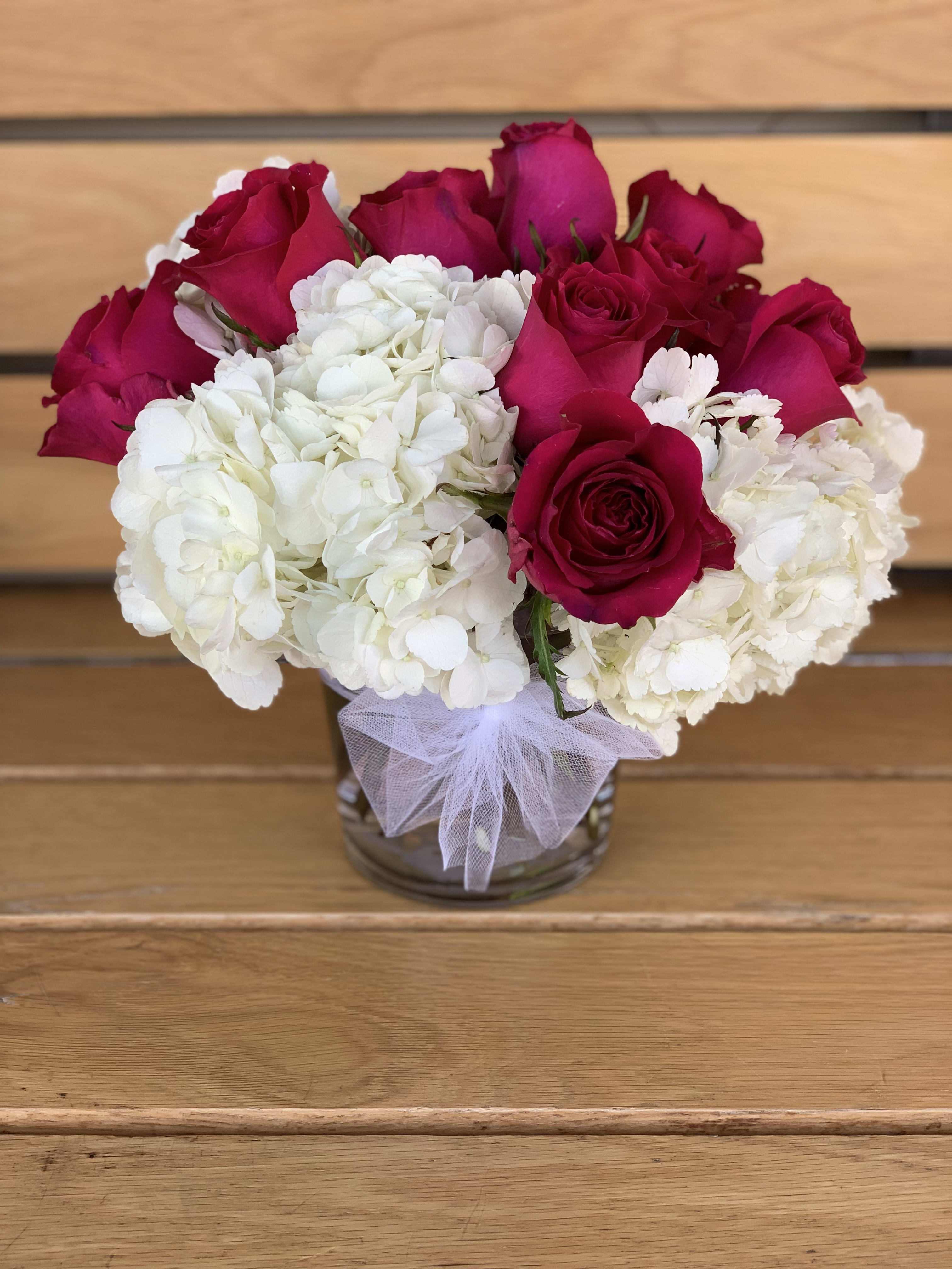 Royal Majesty  - A dozen of hot pink roses arranged in a clear glass vase with white hydrangeas. 