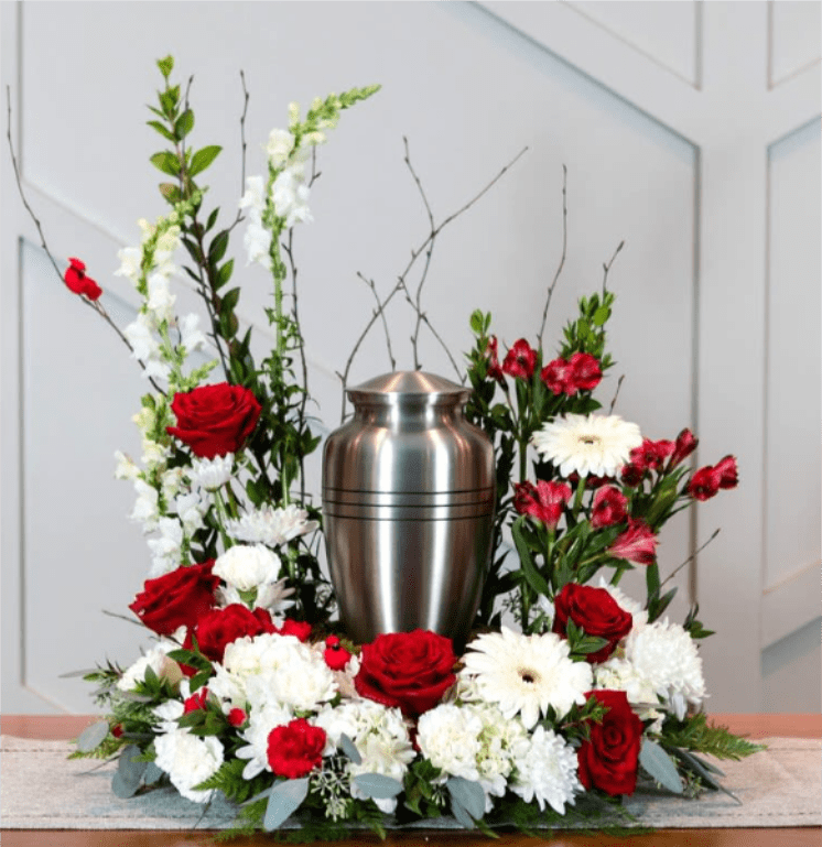 Songbird - A mix of red and white seasonal blooms and red cardinals are used to create a striking frame around an urn.  Approximate Size: 25" Tall by 25" Wide