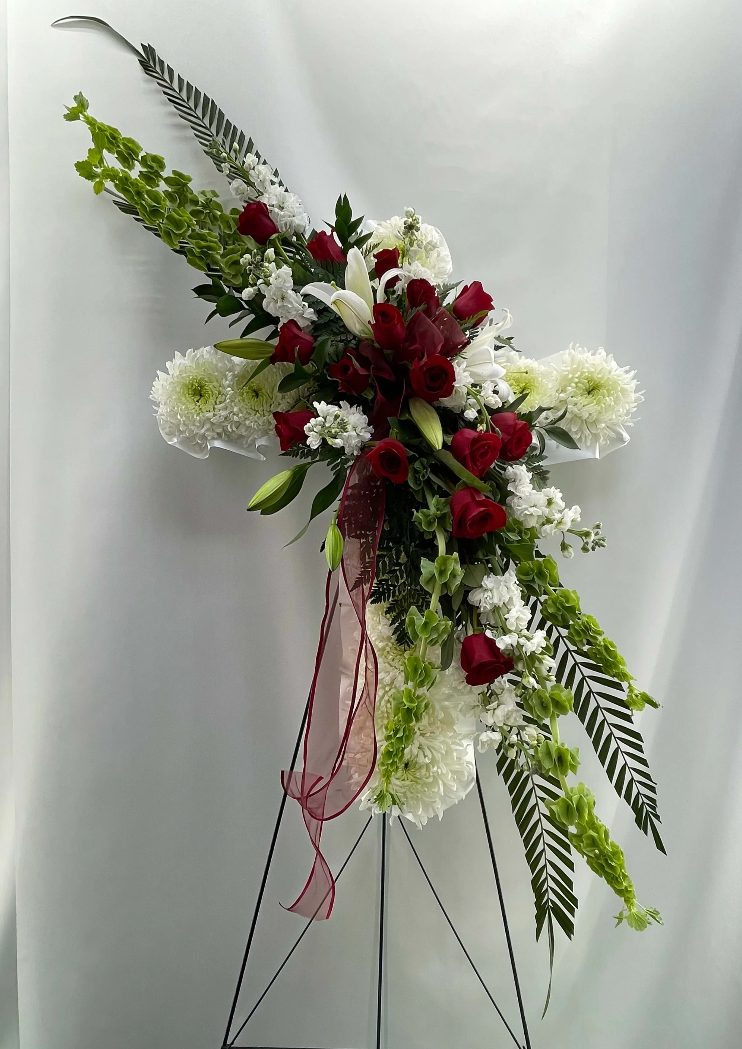 Floral Cross Easel - The FTD Floral Cross Easel is a symbol of love and faith to honor the deceased at the final farewell service. White carnations are arranged to form a cross in which an accent of red roses. Displayed on a wire easel.    38""h x 24""w