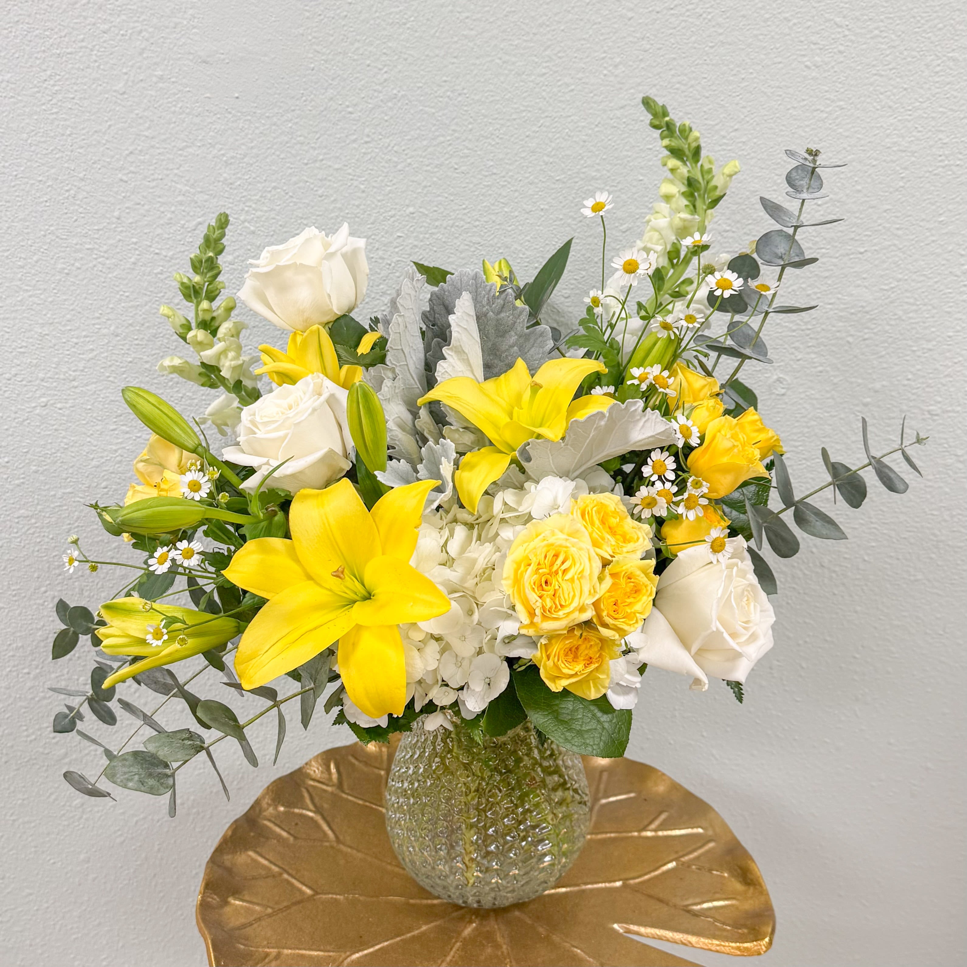 Hello Sunrise - Like the soft glow of the rising sun brighten someone's day with this stunning arrangement of lilies, roses, hydrangea, snapdragons and delicate chamomile. Complimented with soft grey greenery in a cute keepsake dimple vase. 
