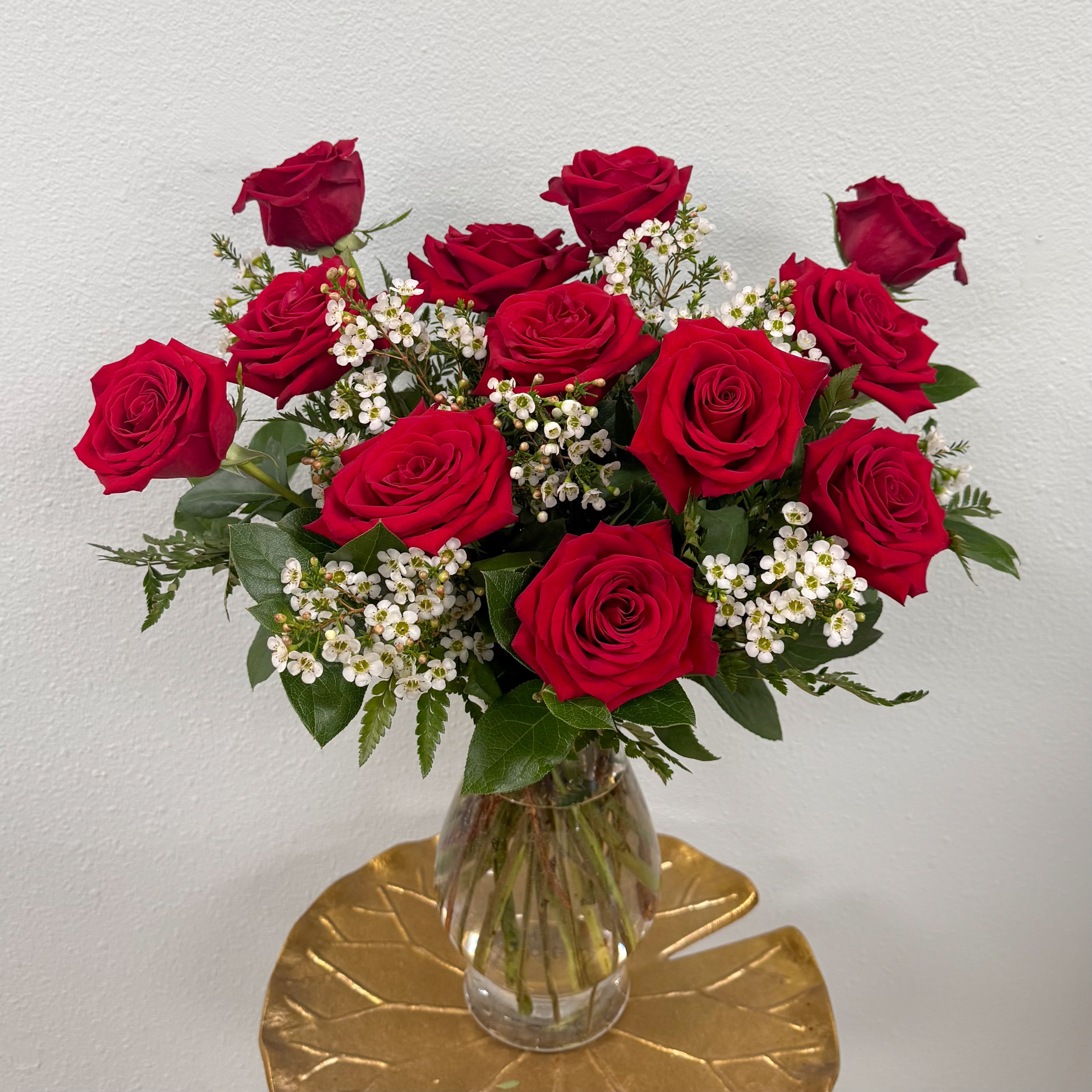 The Luxury Dozen - One dozen premium Ecuadorian roses in an elegant, curved vase complimented by fragrant waxflower. 