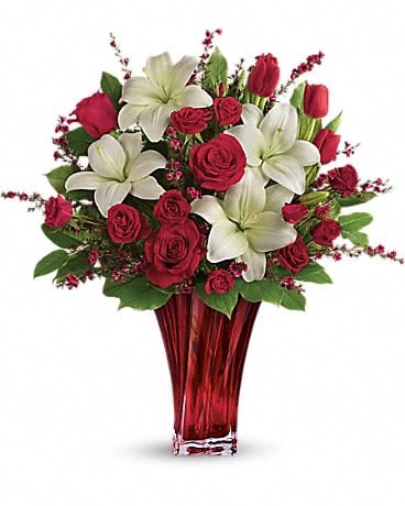 Love's Passion Bouquet  - Classic romance is this radiant bouquet of red roses, crimson tulips and pure white lilies, hand-delivered on Valentine's Day or any day in an exquisite blown glass vase. With its radiant red hue and unique twisting shape, it's sure to take their breath away! This passionate display of red roses, red spray roses, red tulips, and white asiatic lilies is accented with red leptospermum, leatherleaf fern, and lemon leaf. Delivered in a Love's Passion vase. 