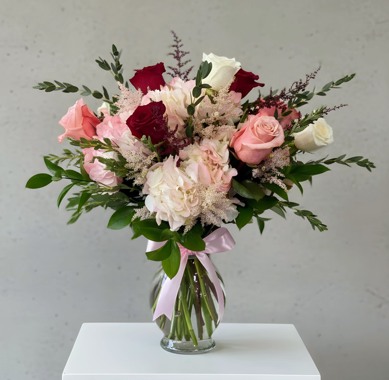 Eleganza d’Amore - A beautifully designed arrangement featuring red, soft white and blush roses paired with lush hydrangeas, finished with luxury greenery and delicate filler flowers. Timeless, romantic, and crafted to elevate any special moment.