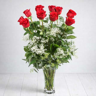 Classic Dozen Red Roses - Product Description  This classic Valentine’s Day flower arrangement of a Classic Dozen Red Roses is presented in a clear glass vase, hand designed by a local East Moline florist with delivery available.  Our Classic Dozen Red Roses features timeless red roses beautifully accented with fine, delicate companion blooms and soft textural details that enhance the arrangement while allowing the roses to remain the focal point, with accent flowers varying based on fresh availability.  Classic Dozen Red Roses is available for Valentine’s Day flower delivery in East Moline, Moline, Rock Island, Silvis, Davenport, and Bettendorf, making it a timeless way to share love throughout the Quad Cities.  Standard: 12 Roses  Deluxe: 18 Roses Premium: 24 Roses  APPROXIMATE DIMENSIONS: 25" H X 18" W