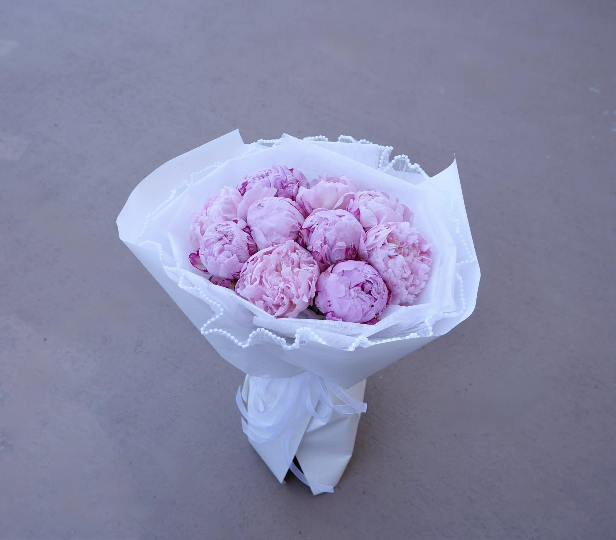 Fresh Peony Blush Charm  - Soft, romantic, and full of charm — this bouquet is a love letter written in peonies.   Ten lush blooms in shades of blush pink and lavender are wrapped in crisp white paper and tied with a satin ribbon, creating a timeless arrangement that feels both luxurious and heartfelt.  Each peony is hand-selected for its fullness and color, bringing texture, elegance, and emotion to the bouquet. Whether you're celebrating love, sending a thoughtful gift, or treating yourself to something beautiful, this arrangement speaks softly but deeply.  Let the charm of peonies brighten your day — or someone else's.