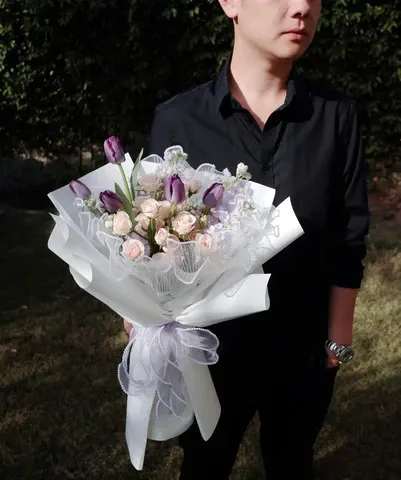 Lavender Grace – Designer’s Choice Bouquet - A graceful blend of tulips, stock flowers, and roses, this bouquet is thoughtfully arranged to showcase soft textures and romantic hues. Wrapped in crisp white paper with a lavender ribbon and mesh detail, it’s designed to highlight the natural beauty of each bloom. This is not a random mix — every flower is chosen for its freshness and harmony, making it a perfect gift for birthdays, anniversaries, or heartfelt moments.