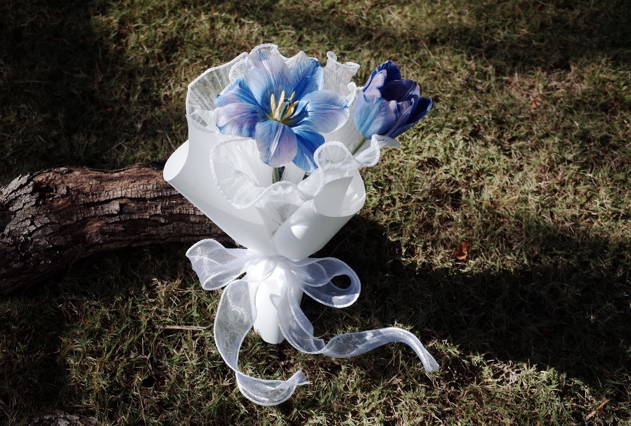 Magic Blue Tulip - Small Budget Big Love - A little bouquet with a big heart.   This charming arrangement features soft blue tulips blooms, wrapped in crisp white paper and tied with a sheer ribbon. It’s perfect for small gestures with big meaning — birthdays, thank-you, or just because.  Affordable, sweet, and full of love — this bouquet proves that beauty doesn’t need a big budget.