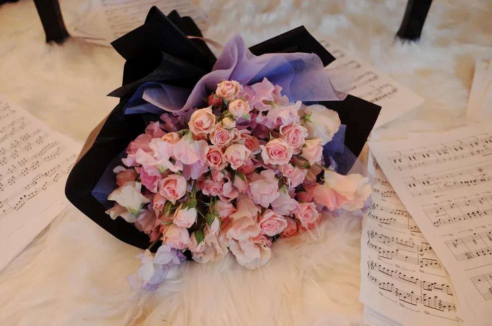 Romantic Fresh Bouquet – Melody of Love  - A symphony of soft petals and tender hues, Melody of Love captures the poetry of romance in every bloom. Featuring blush pink roses and pastel florals wrapped in dramatic black and violet paper, this bouquet evokes the feeling of a love song played from the heart. Perfect for anniversaries, performances, or heartfelt gestures, it’s a floral composition that speaks without words.
