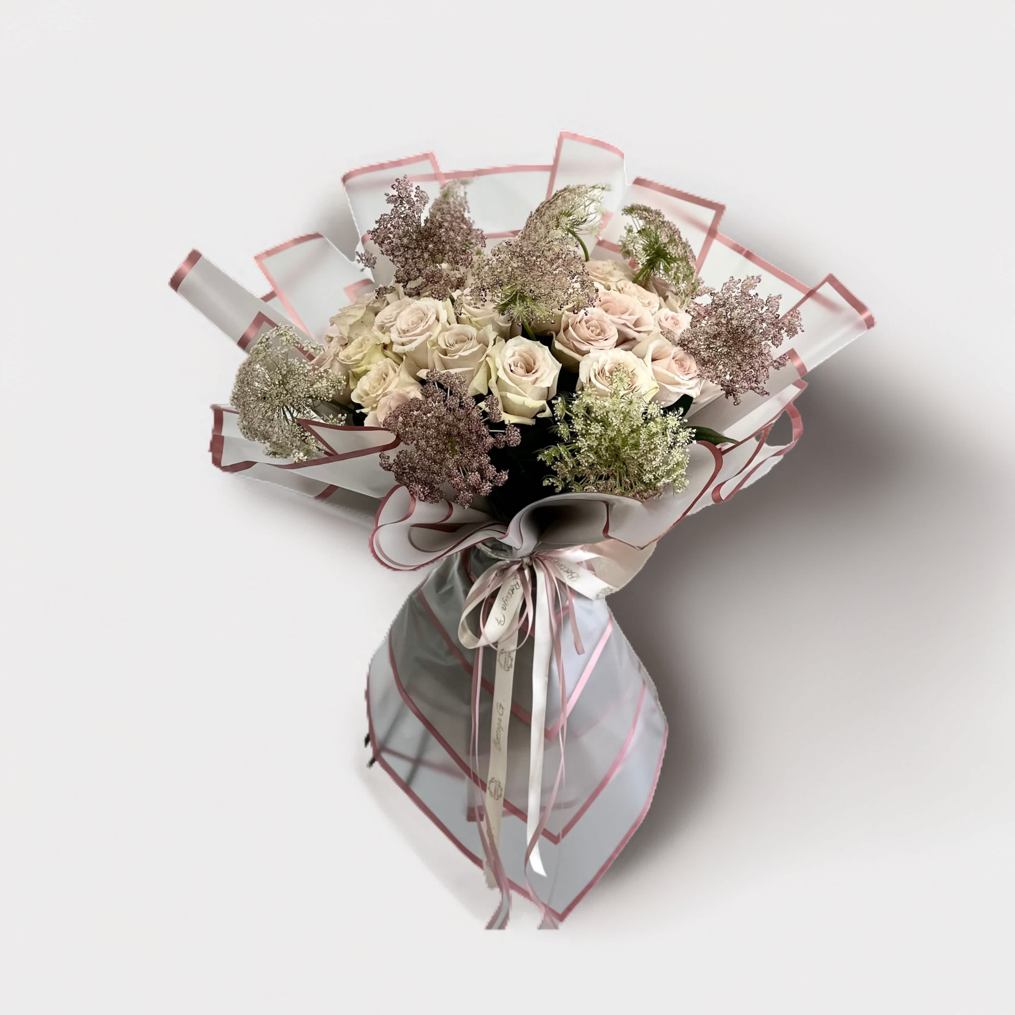 Timeless Beauty Bouquet - Picture an elegant ivory bouquet, exuding timeless beauty and sophistication. This stunning arrangement features a harmonious blend of ivory-hued blooms, each selected for its delicate charm and graceful appearance. At the heart of the bouquet are classic ivory roses, their velvety petals unfolding in perfect symmetry. These roses are complemented by creamy white peonies, their lush, full blossoms adding a touch of romance and opulence.  Surrounding these central flowers are delicate ivory calla lilies, their sleek, trumpet-shaped blooms adding an element of modern elegance. Interspersed throughout the arrangement are clusters of dainty ivory ranunculus, their layers of petals creating a soft, ruffled texture.  To add depth and contrast, the bouquet is accented with sprigs of soft green foliage, such as eucalyptus and dusty miller, which enhance the ivory tones without overpowering them. The stems are wrapped in a satin ribbon of matching ivory, tied in a neat bow, completing the refined and cohesive look.