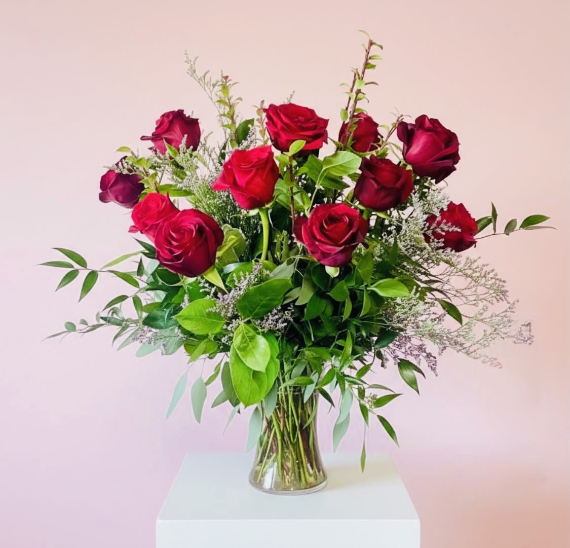 A Dozen Reasons Why I Love You - The perfect dozen roses to classically say, I love you or congratulations for any special occasion. Remind them how important they are to you by showering them with love in the language of flowers. This beautiful glass vase holds a dozen premium red roses mixed with gorgeous red tulips, scabiosa and mixed greens. Finished of with a glittery red heart.