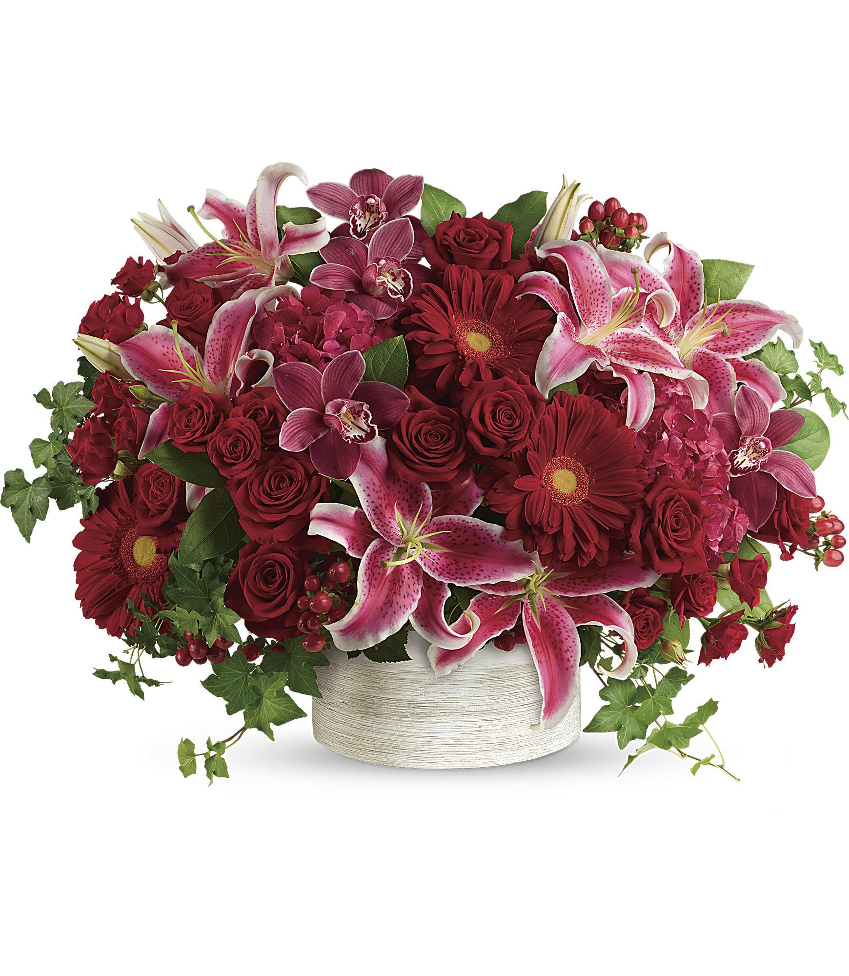WCF Luxe Collection - Statement of Love - Brimming with stock, orchids, roses and lilies in fabulous fuchsias and radiant reds, this breathtaking bouquet definitely makes a statement! Oh my!  This stunning arrangement of red stock, red cymbidium orchid blossoms, red roses, red spray roses, hot pink oriental lilies, red gerberas, and red hypericum is accented with green ivy and lemon leaf. Delivered in a white cylinder planter. Approximately 24 3/4" W x 17 1/2" H  Please note that orders must be placed a least 48 hours prior to fulfillment date in order to procure the freshest and highest quality blooms. 