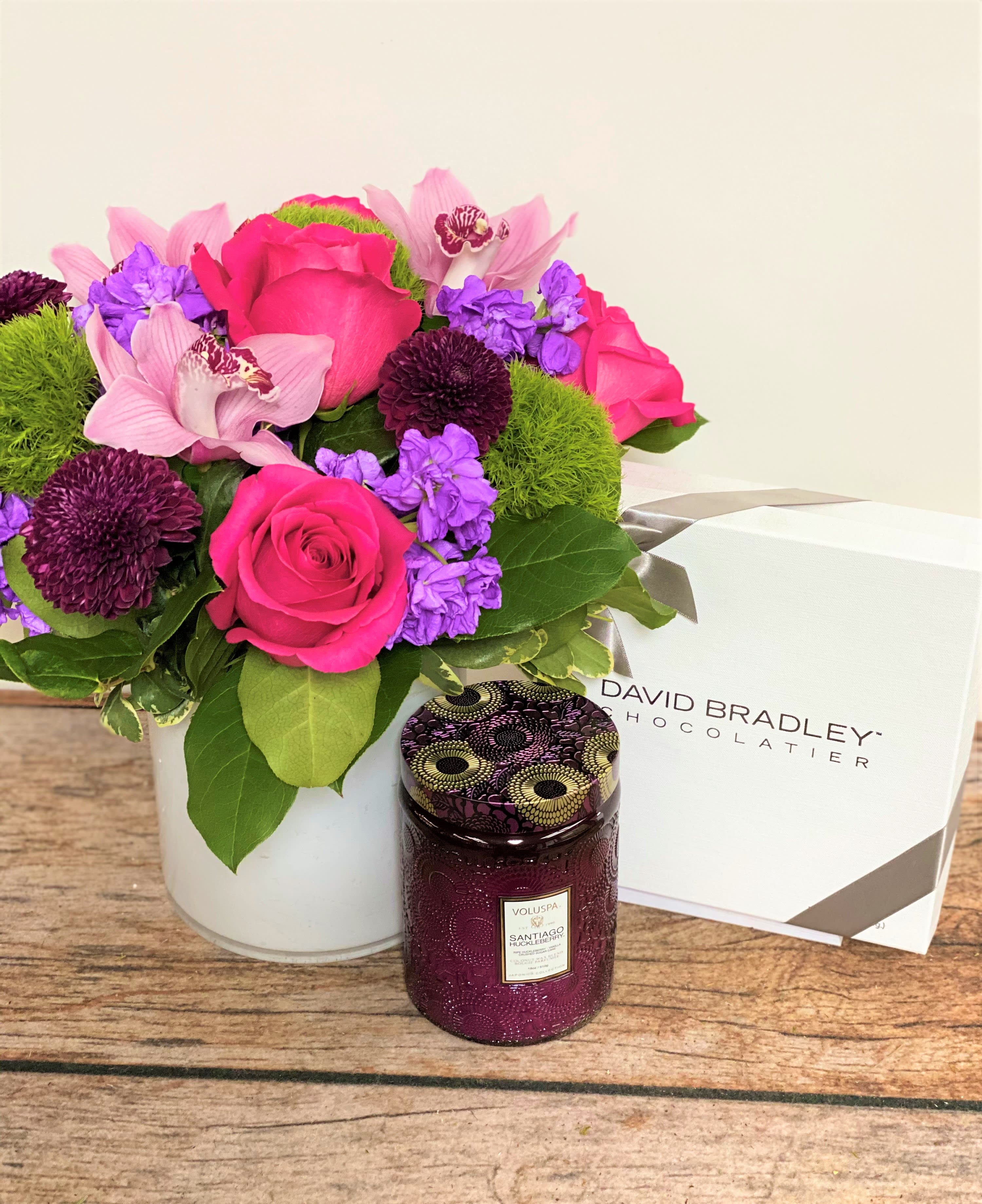 The Complete Package - All packaged and ready to go! A full, mixed floral arrangement accompanied by a Voluspa candle a half pound box of mixed David Bradley Chocolates. Everything they need!