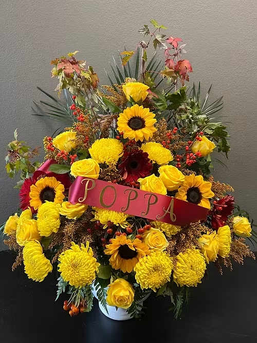Sympathy The One and Only - A bright one sided arrangement with yellow roses, sunflowers and filler flowers.