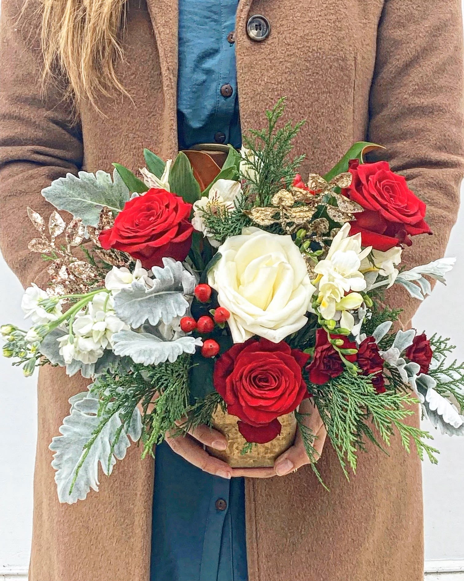 Winter Charm - The Winter Charm is a petite yet striking arrangement that captures the cozy spirit of the season. Featuring velvety red roses paired with delicate white stock and alstroemeria, this design offers a beautiful contrast of bold and soft tones. Accented with vibrant red hypericum berries, fragrant cedar, and silvery dusty miller, it evokes the crisp elegance of winter days. Perfectly sized for intimate spaces, the Winter Charm brings a festive touch of warmth and sophistication to your holiday décor.