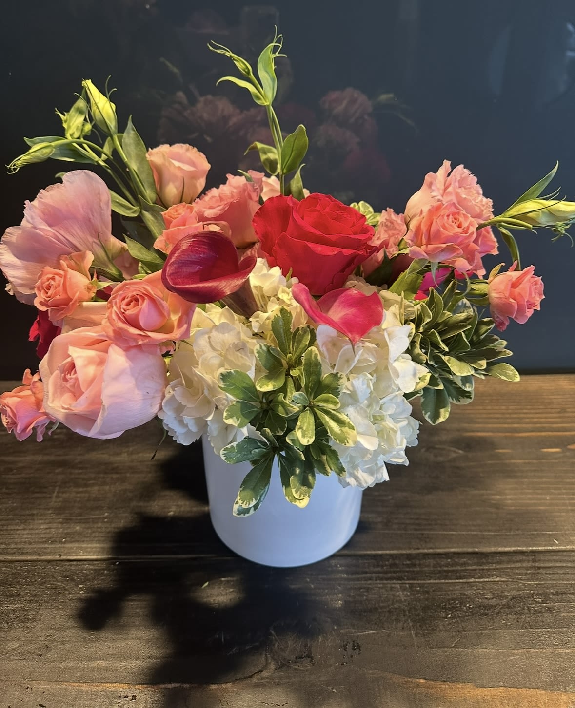 Pink Petals  - A white ceramic vase filled with different shades of pink roses, hydrangeas, calla lilies and touch of greenery.