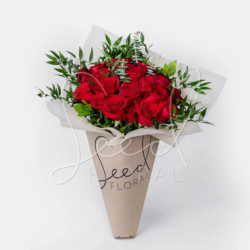 24 Carat Rose Bouquet- VDAY - Our 24 Carat bouquet showcases 24 luxurious long-stemmed red roses, hand-tied with fresh greenery and eucalyptus for an elegant finish. Symbolizing love, passion, and devotion, this striking arrangement is the ultimate romantic gesture—perfect for anniversaries, Valentine’s Day, birthdays, or any occasion worth celebrating in style.  Presented in a modern kraft wrap, the 24 Carat bouquet combines timeless beauty with sophistication, making it a truly unforgettable gift. Each rose is carefully selected for freshness and quality, ensuring your message of love is delivered with elegance.