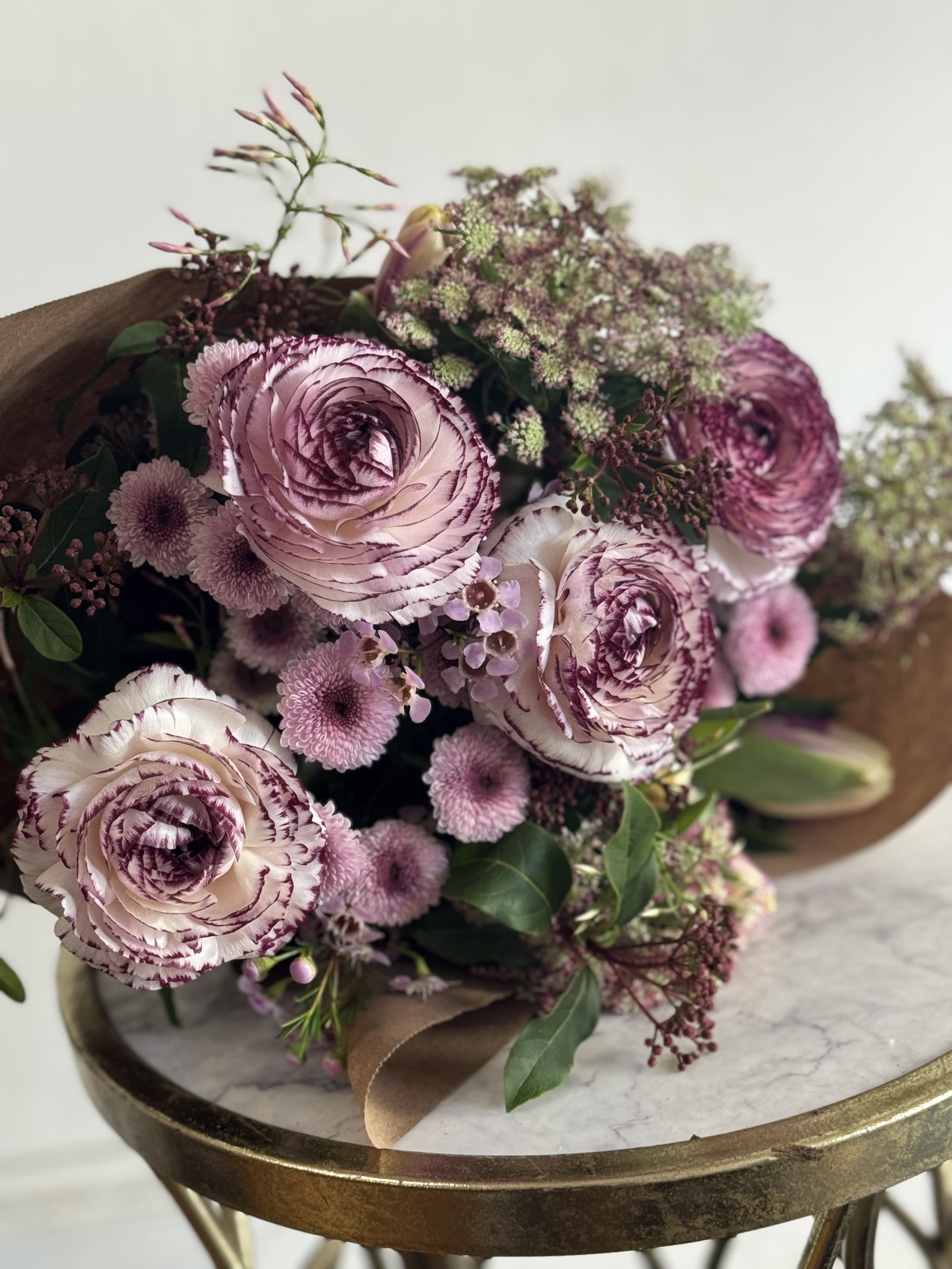 Purple Darling  - Short and sweet sampling of purple flowers. From low lavender to dark purple , we will gather pretty purple designers choice blooms and we will paper wrap them with a bow and send them off as a quick "Thank you"! or " I love you" or "Happy Birthday!"  *VALENTINE'S DAY DELIVERIES ARE LIMITED SO ORDER EARLY! PLEASE CALL THE SHOP TO PLACE ORDER IF THEY NEED TO BE TIMED* ** This is an approximate picture of what the arrangement will look like the week of Valentine's Day Weekend February 9, 2026 - February 14, 2026 ** If any design element such as color or flower/foliage are very important to your order please contact us to ensure availability first by calling the shop at 415 751 2747