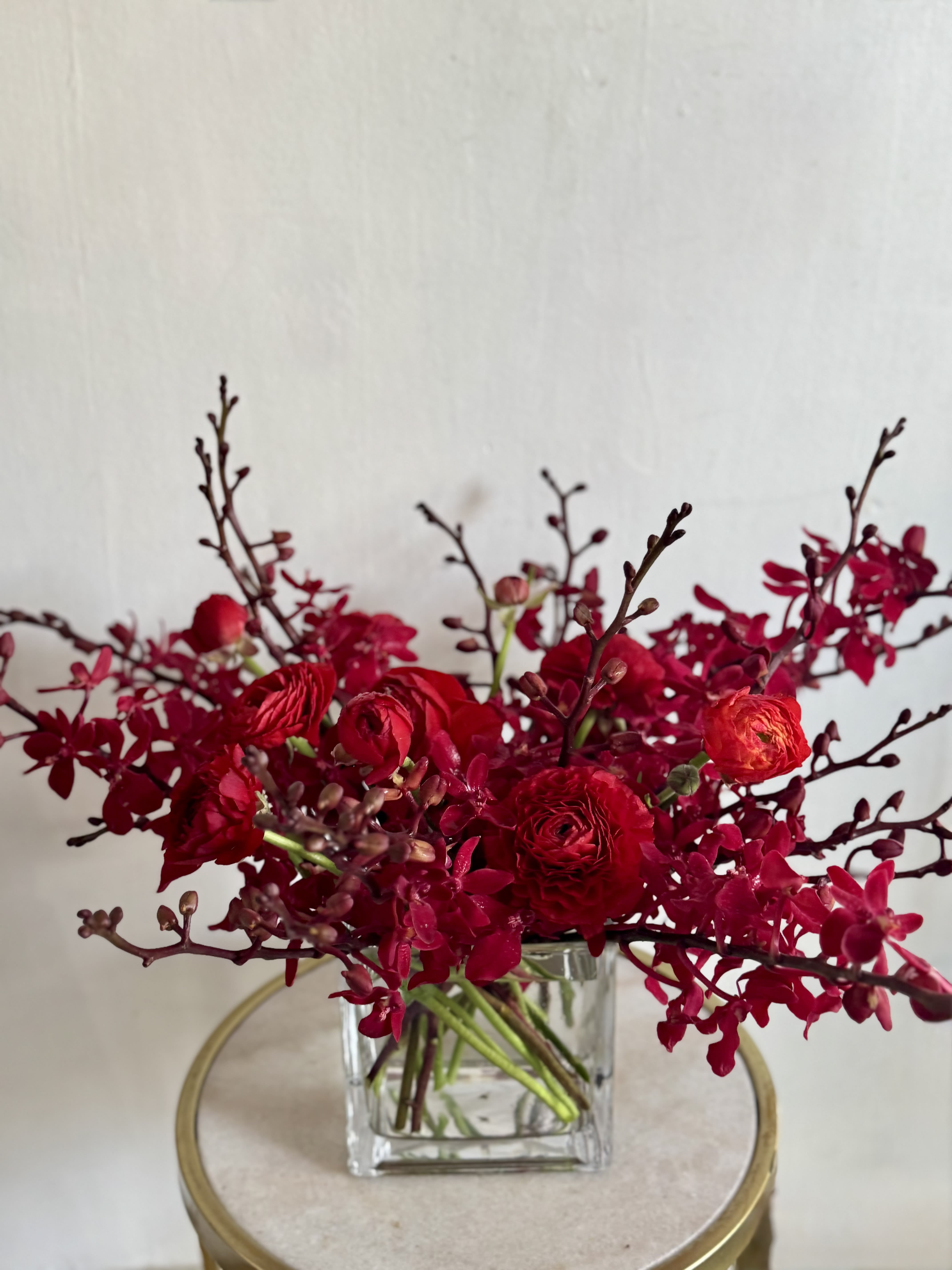 Red Orchids  - Gorgeous, modern, mix or red orchids and a red focal flower. Could be a ranunculus, could be a rose, or calla lily. Whatever it is, it will be gorgeous! Picture is for scale and to illustrate a red monochromatic design.   *VALENTINE'S DAY DELIVERIES ARE LIMITED SO ORDER EARLY! PLEASE CALL THE SHOP TO PLACE ORDER IF THEY NEED TO BE TIMED* ** This is an approximate picture of what the arrangement will look like the week of Valentine's Day Weekend February 9, 2026 - February 14, 2026 ** If any design element such as color or flower/foliage are very important to your order please contact us to ensure availability first by calling the shop at 415 751 2747