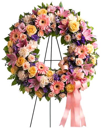 Graceful Funeral Flowers Wreath - Express your love and remembrance with this heavenly floral tribute in gentle shades of pink, peach, lavender and cream. Designed in a meaningful circle of life and love, this Graceful Sympathy Wreath symbolizes hope and eternity. Featured flowers include Ecuadorian Roses, Lilies, Gerbera Daisies, Carnations, Larkspur, Limonium or similar seasonal favorites. Appropriate for wakes, funerals, and memorial services. A beautiful testimonial to a beautiful life. Displayed on 60in tall easel stand.  Standard - 18in Wreath - Overall Size (With Flowers) 22in (H) x 22in (W) - 60in Tall Easel Stand Deluxe - 22in Wreath - Overall Size (With Flowers) 26in (H) x 26in (W) - 60in Tall Easel Stand Premium - 24in Wreath - Overall Size (With Flowers) 28in (H) x 28in (W) - 60in Tall Easel Stand  Please Note: This is a special order floral arrangement. Place your order online and allow at least 1-2 business days for order processing. Please give us a call at 619-237-8842 for same day delivery options. Some substitutions may be necessary due to seasonal availability of certain flowers used in this composition. We can assure you that your order will only be upgraded with same or higher value premium blooms if a substitution is unavoidable.