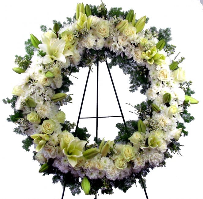 Serenity Funeral Flowers Wreath - A beautiful outpouring of pure white blossoms in an eternal ring to symbolize unending love, admiration, hope, and caring. Featured flowers include premium Roses, Lilies, Carnations, Spray Chrysanthemums, or similar fresh cut favorites. A heavenly tribute and comfort to loved ones. Appropriate for wakes, funerals, and memorials. Displayed on a 60in tall easel stand.  Standard - 18in Wreath - Overall Size (With Flowers) 22in (H) x 22in (W) - 60in Tall Easel Stand Deluxe - 22in Wreath - Overall Size (With Flowers) 26in (H) x 26in (W) - 60in Tall Easel Stand Premium - 24in Wreath - Overall Size (With Flowers) 28in (H) x 28in (W) - 60in Tall Easel Stand  Please Note: This is a special order floral arrangement. Place your order online and allow at least 1-2 business days for order processing. Please give us a call at 619-237-8842 for same day delivery options.