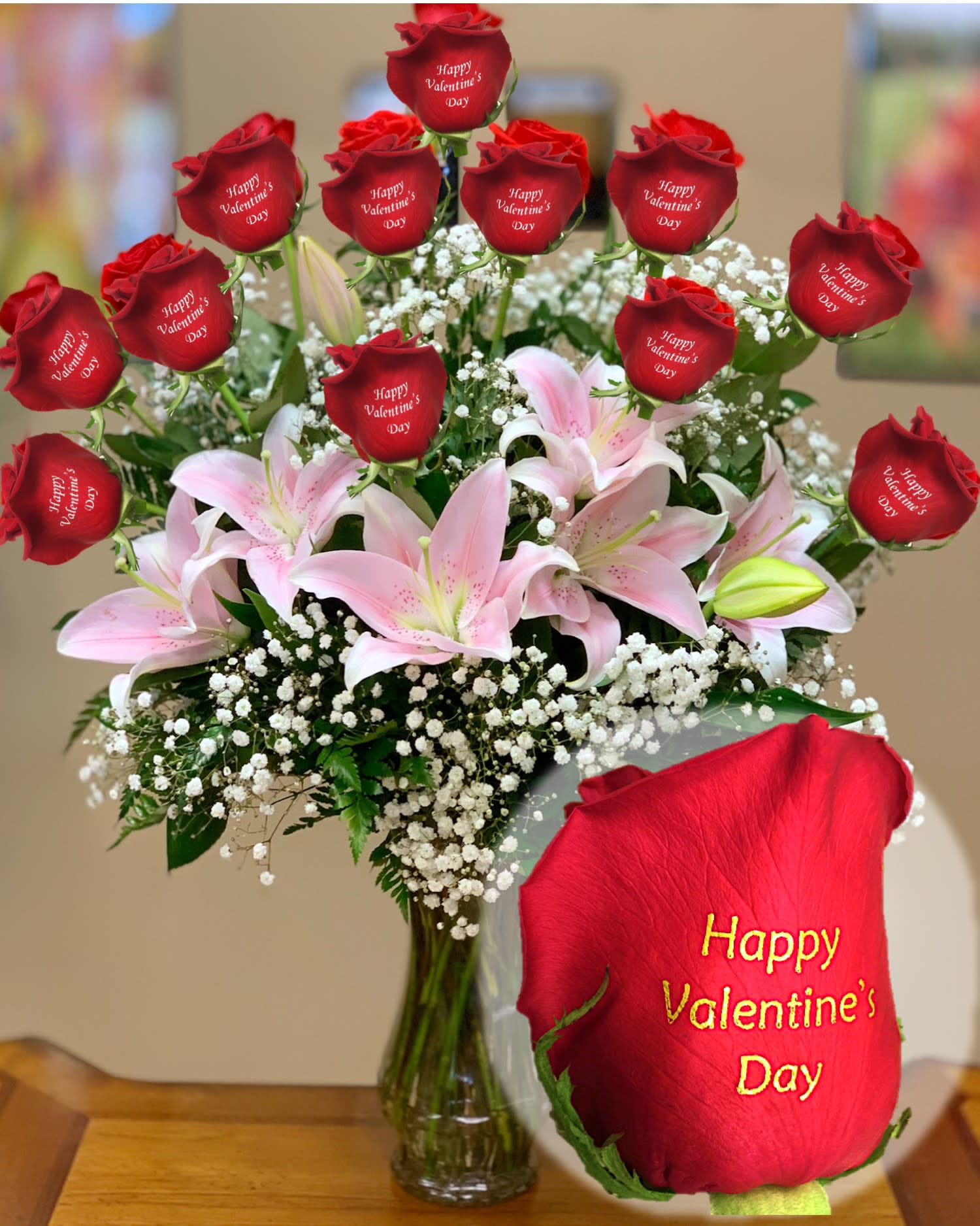 Happy Valentine's Day 2026 - 12 personalized red roses printed with ,,Happy Valentine's Day '' message and stargazer lilies arranged in a vase.  As Shown ( 12 red roses and 3 lilies )   Deluxe ( 17 red roses and 4 lilies )   Premium ( 21 red roses and 6 lilies ) 