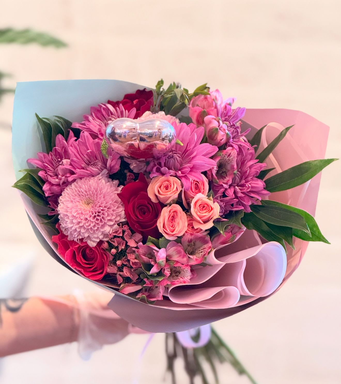 Treasured Love Wrapped Bouquet with Roses - Hand-wrapped mixed flower bouquet with roses. Wrapped beautifully in Korean papers. Tied off with a bow and finished with a heart pick. Paper colors may vary. 