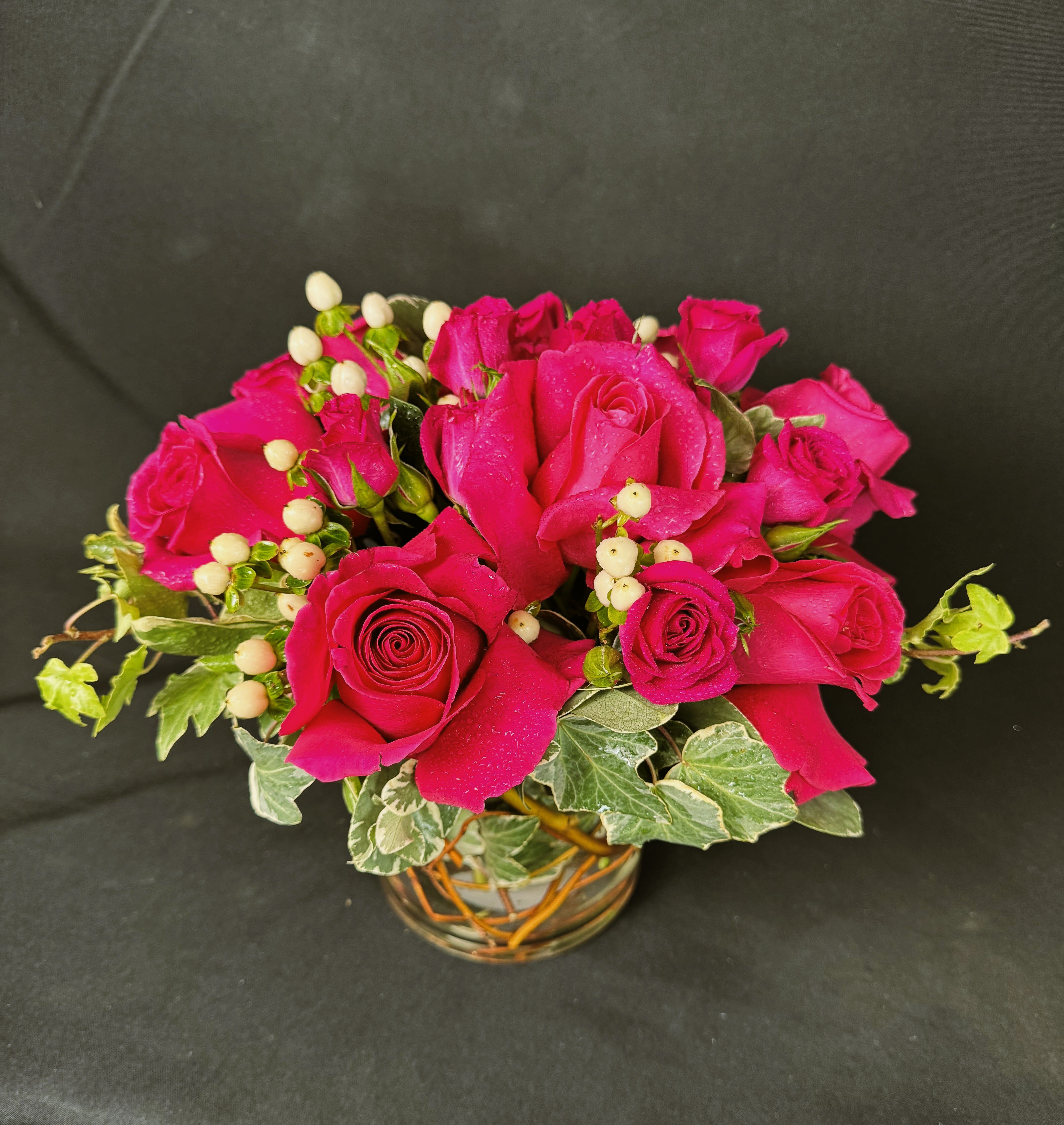 Hot Hot Hot - Turn up the heat with our Hot, Hot, Hot floral arrangement! Featuring a stunning ensemble of fiery fuchsia roses, accented with delicate white hypericum berries and lush ivy, this design is the epitome of passion, elegance, and sophistication. Set in a charming woven vase, this arrangement exudes a modern yet timeless allure, making it the perfect gift for romantic occasions, birthdays, celebrations, or just because! Let this vibrant bouquet speak volumes—whether you're expressing love, admiration, or appreciation, Hot, Hot, Hot is sure to make hearts race and leave a lasting impression.  Order now and ignite the moment with flowers that captivate! 