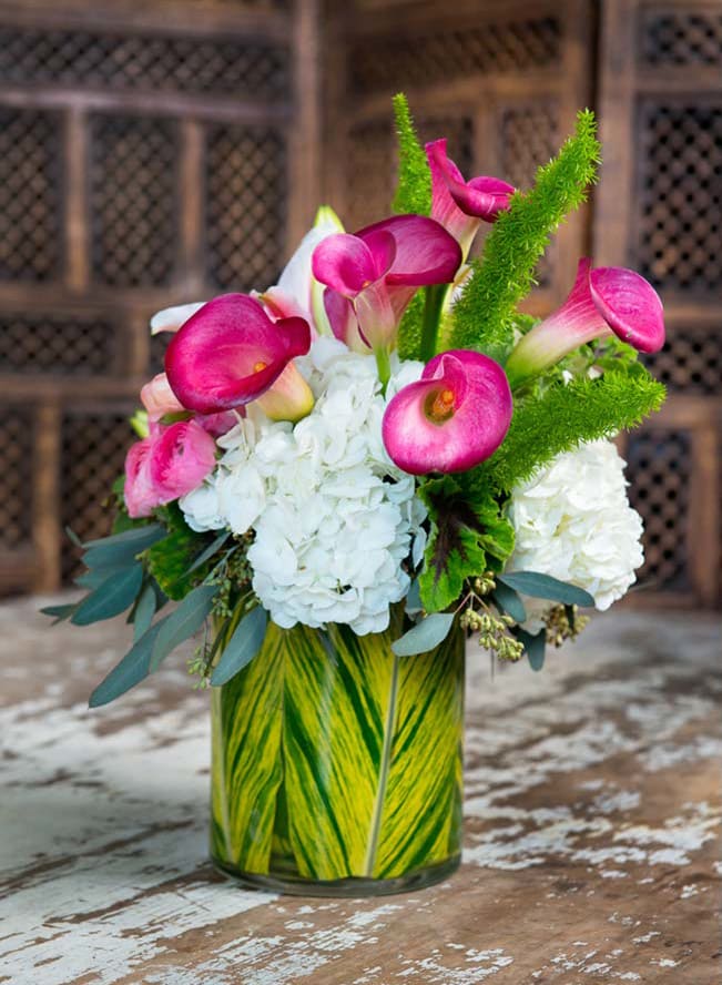 Calltastic - Hydrangea, Colored Calla lilies, and exotic foliage as well as a ginger leaf lined rectangular glass vase.
