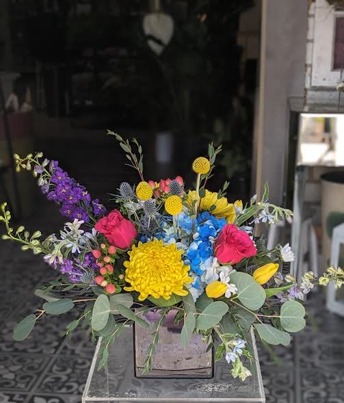 Blue Caribbean Breeze (Designer Choice) - This is designed in a blue cube.  We will try to stay within the color scheme of the flowers. Please note that the flower selection may change. All Around Approx 13"Hx8"W