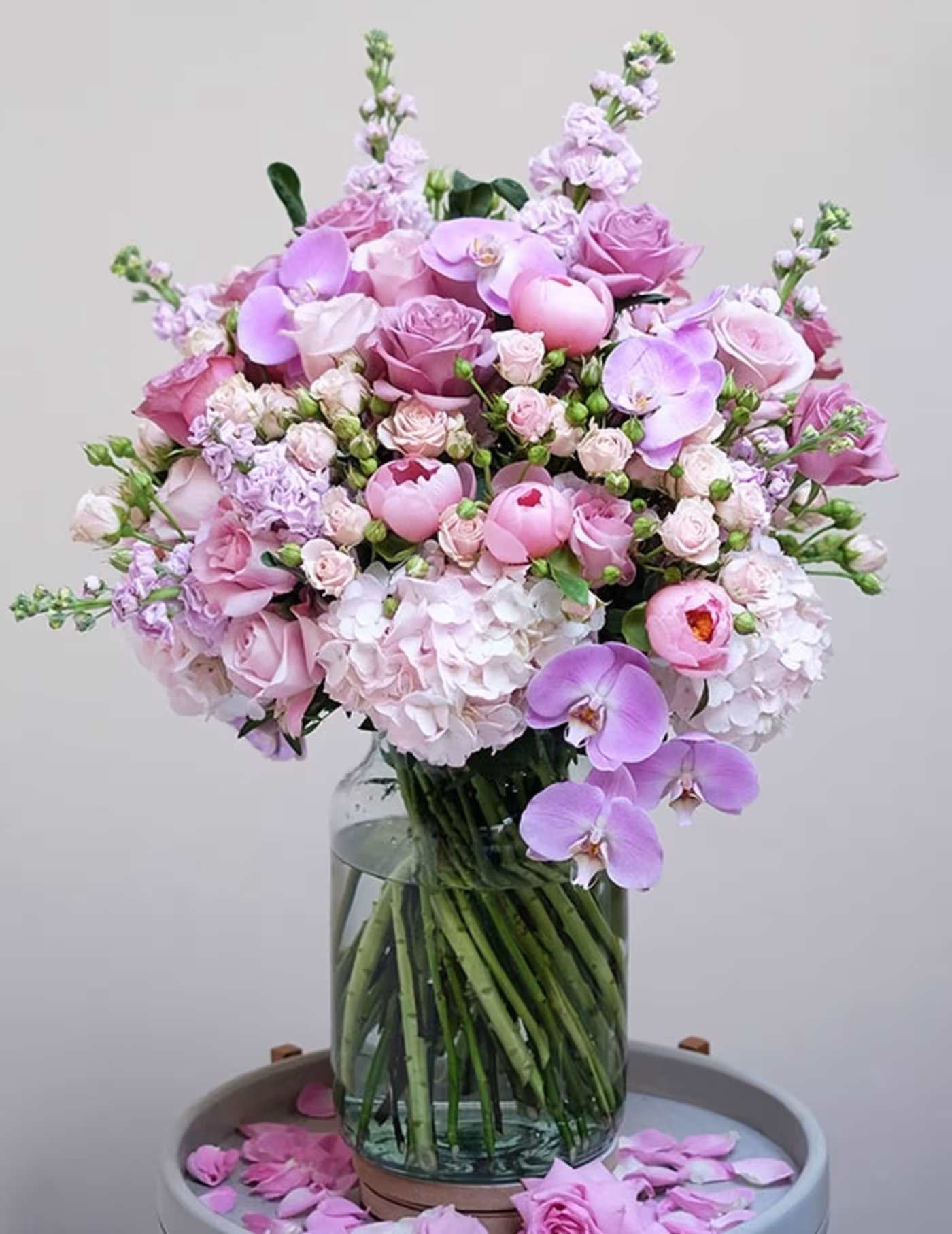 Summer Breeze    flower   bouquet - This exquisite flower bouquet in rich shades of pink showcases a captivating ensemble of roses, hydrangeas, peonies, and orchids, thoughtfully selected to create a harmonious blend of colours and textures. Presented in a minimal clear glass vase that adds a touch of modern simplicity, accentuating the grandeur of the floral arrangement. Whether adorning your home, office, or special event, this luxurious bouquet promises to leave a lasting impression.