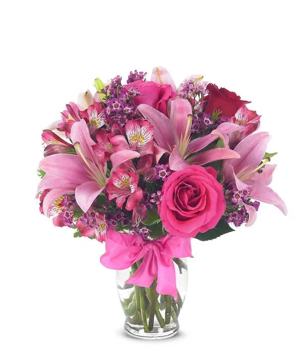 Made with Love - Send stunning flowers to celebrate any occasion! With classic floral colors including red roses and pink lilies, the Rose and Lily Celebration is a wonderful gift to send to a friend or family member for a birthday, get well or anniversary. The flowers are arranged by hand at a local florist shop. The floral artist creates the Rose and Lily bouquet with red roses, pink roses, pink lilies, pink alstroemeria and purple waxflower. Paired with the flowers is a keepsake clear vase that is wrapped in a decorative ribbon. Measures 14"H by 12"L.   Includes:  • Pink Asiatic Lilies  • Pink and Red Roses  • Purple Waxflowers  • Alstroemeria  • Glass Vase