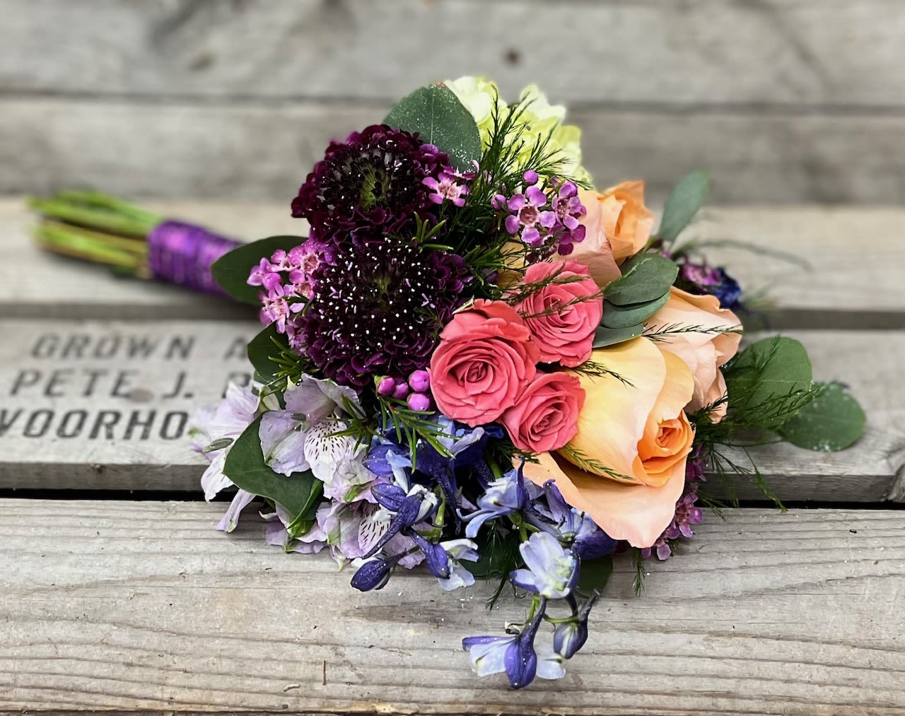 Prom Nosegay - Black Dress - Mix of all dark and deep color flowers, burgundy, blues, purples arranged beautifully in small handheld handpicked look will have a variety of filler and eucalyptus greens. Stems will be wrapped in your choice color sheer ribbon. Ribbon color is to compliment dress color not exactly match. All bouquets will be finished with light glitter.  Please note in special instructions what color ribbon and any other special requests.  Bouquets typically contain a mix of roses, spray roses, alstroemeria, daisies, stock, hydrangea, snap dragons, carnations, mini carnations, fillers and greens    Bouquet will not match the photo exactly, as each nosegay is uniquely hand made by our designer. Will have same look, feel and size.  