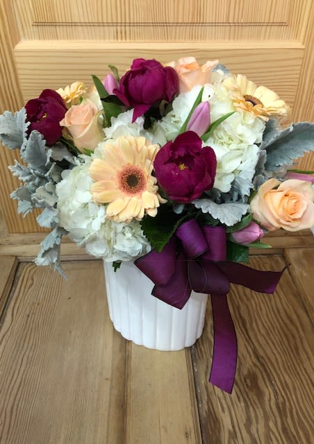 A subtle WOW arrangment - This WOW arrangement is made pave on a white container and filled with high end gorgeous blooms. Not a lot of extra greenery in this one... just gorgeous blooms and rich hues. 