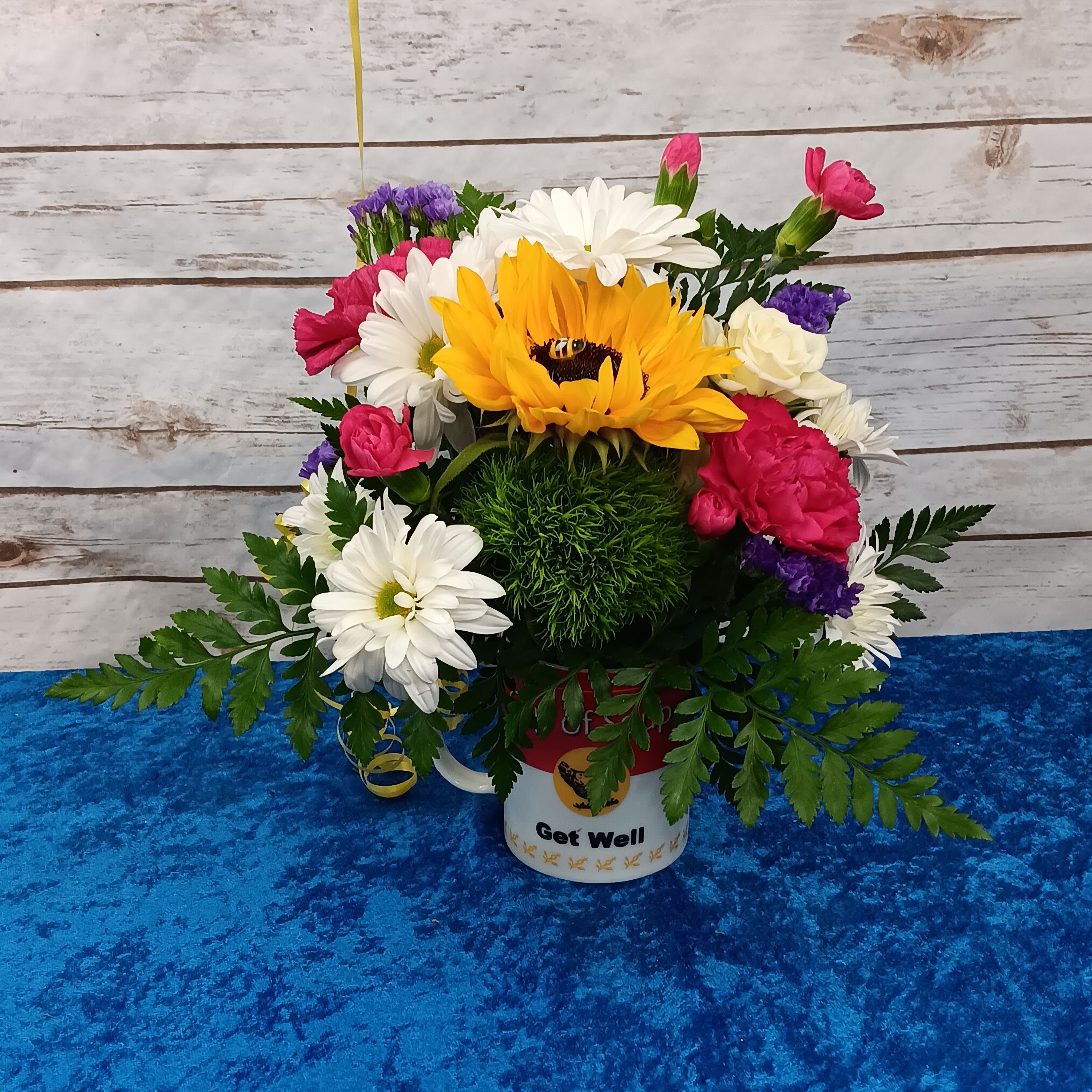 Bee Well, My Friend with a Sunflower  - Lift their spirits with our BEE WELL, MY FRIEND bouquet. Each bouquet is one-of-a-kind, just like your friend or loved one, and perfectly petite for a bedside table.  Our designer will create an arrangement in a Cup of soup, Get Well Mug, from the freshest flowers available.     