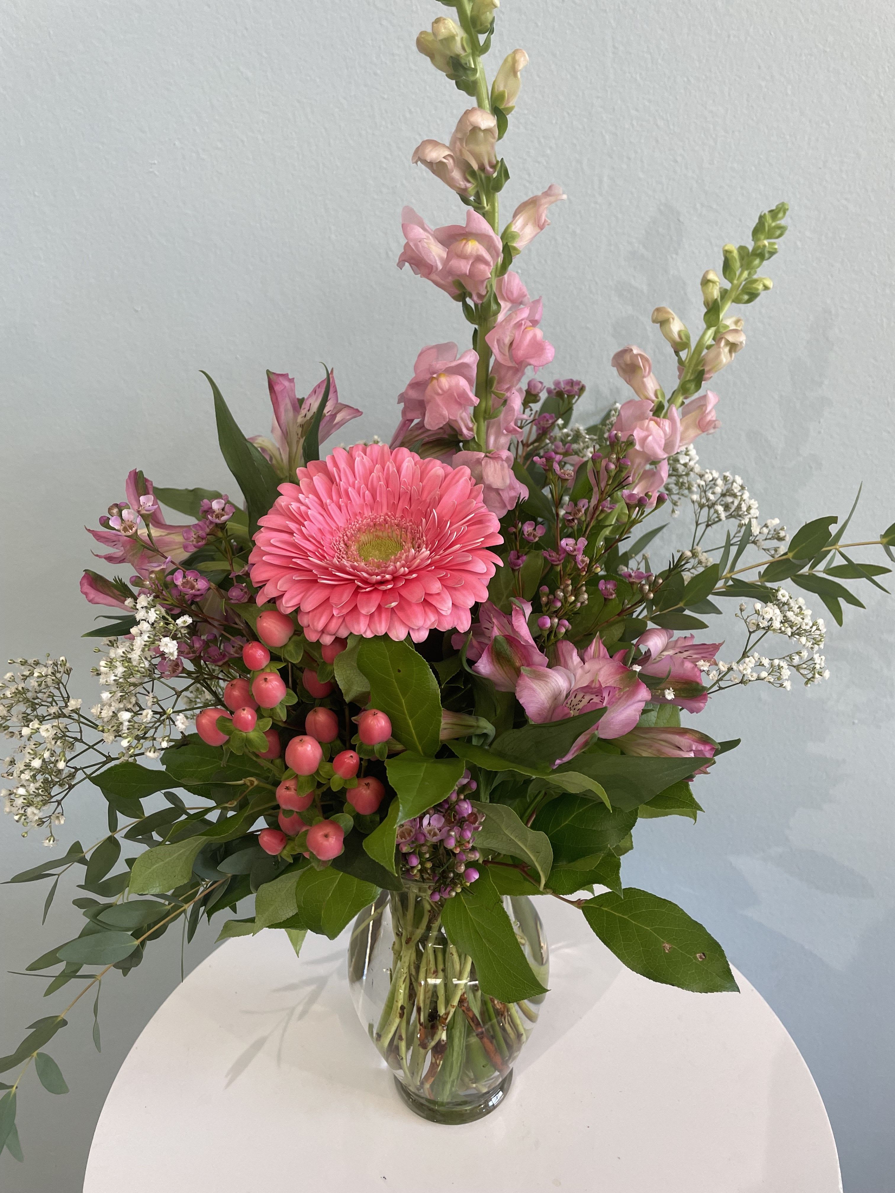 Tickled Pink - This small arrangement is the perfect gift for someone in your life who adores the color pink! Coming in all different shades of pink, this arrangement may include a gerbera daisy, snap dragons, and pink hypericum berries. This fragrant arrangement includes a plethora of greenery and is sure to put a smile on anyone's face.
