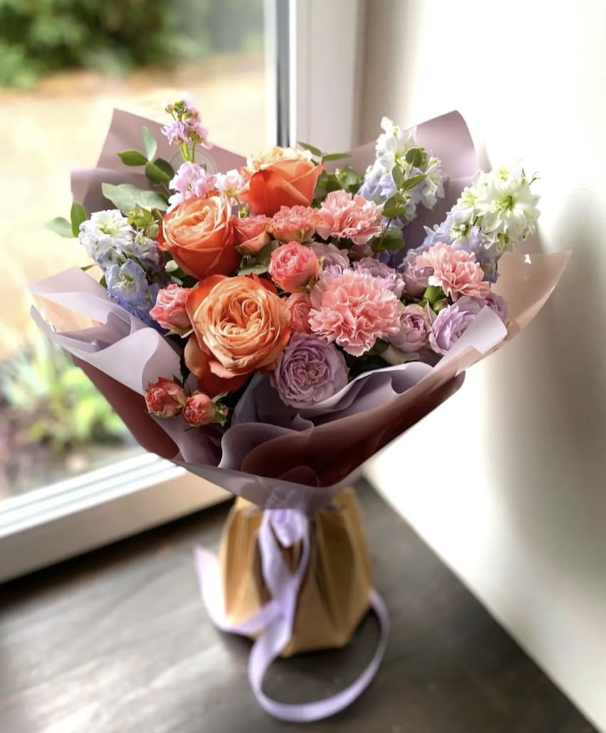 Designer's Choice wrapped bouquet  - Let our Florists design a WRAPPED Bouquet full of lovely and gorgeous blooms! Each arrangement in this style is handcrafted and one of a kind. Includes 6 roses, one Lilly, and a variety of flowers all wrapped together.