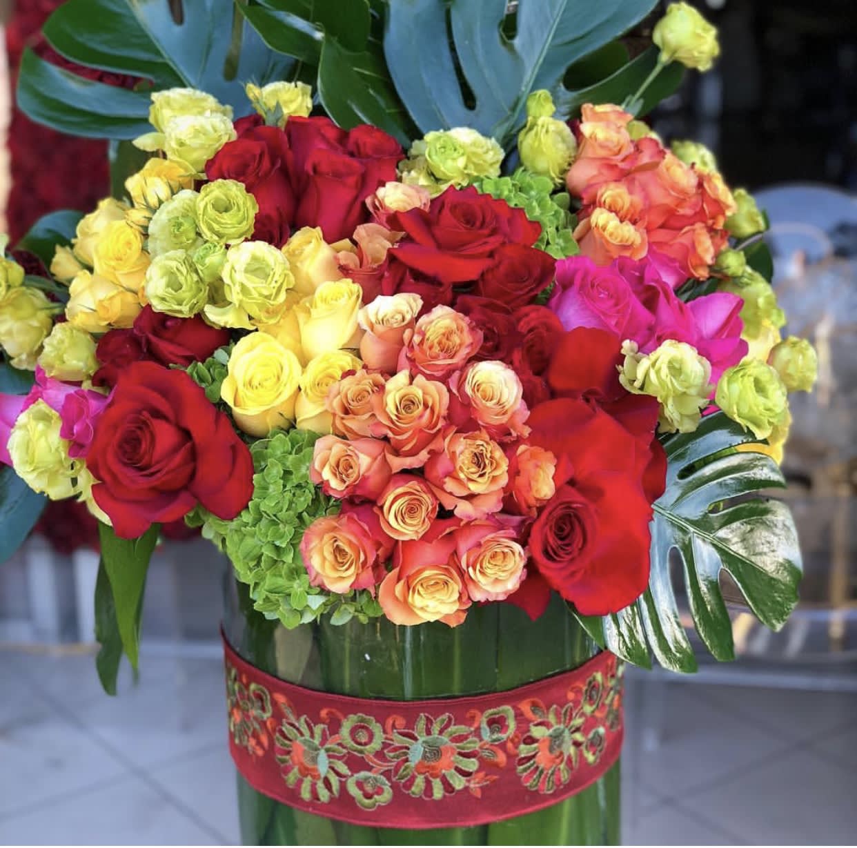 Year of the HORSE - Large, wide cylinder adorned in green leaves filled with a colorful array of flowers exuding joy.