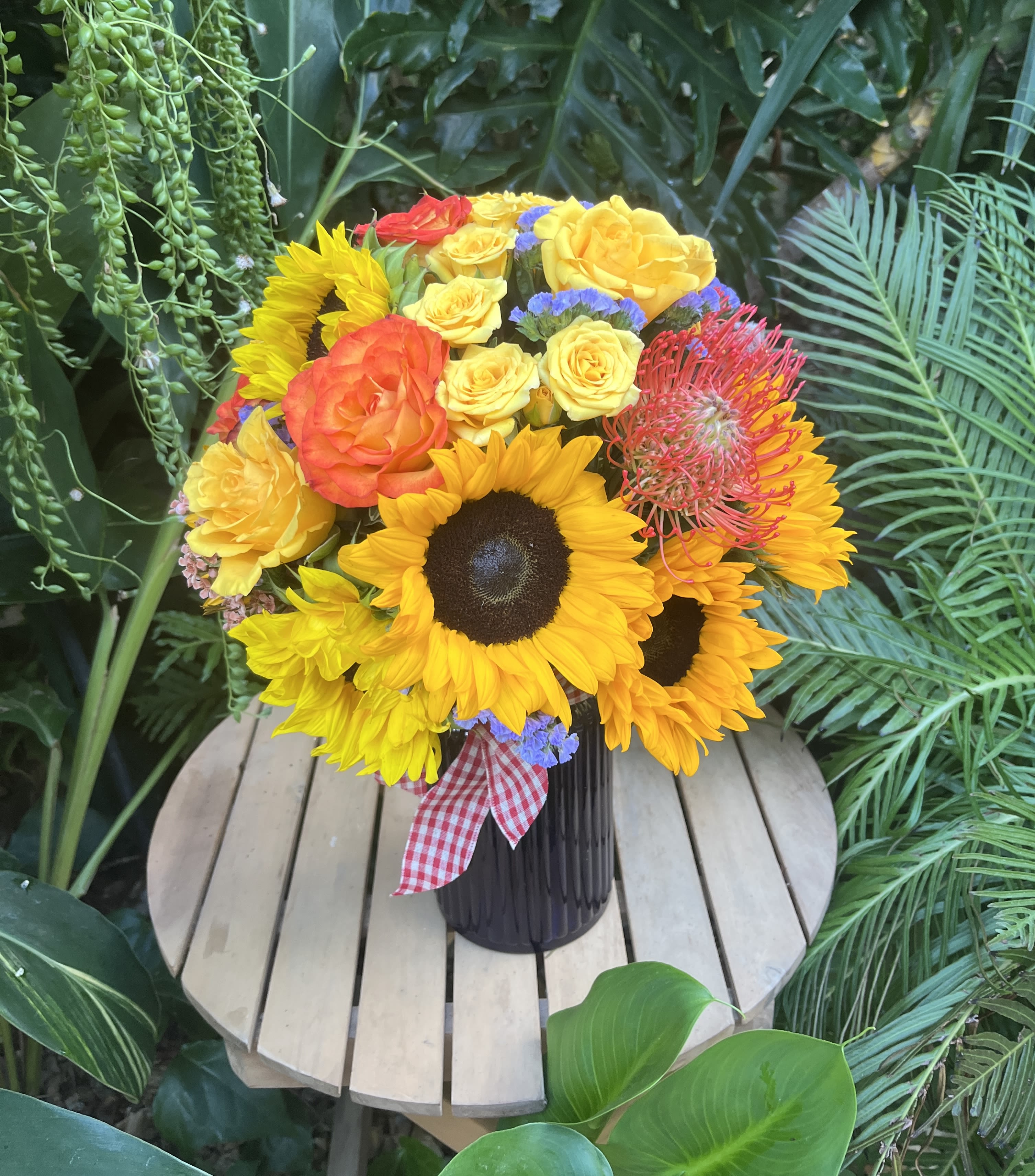 Our Story - Hand-crafted mixed flower bouquet in a blue vase. Each purchased arrangement may differ from the photo due to natural variability in the shape and coloration of natural blossoms. The main flowers in this arrangement are sunflowers, and the rest are chosen by the designer based on the season and availability. If you would like to request specific flower types and colors, please place your order in the Custom Arrangements section where you can specify those details or give us a call to discuss your ideas. 