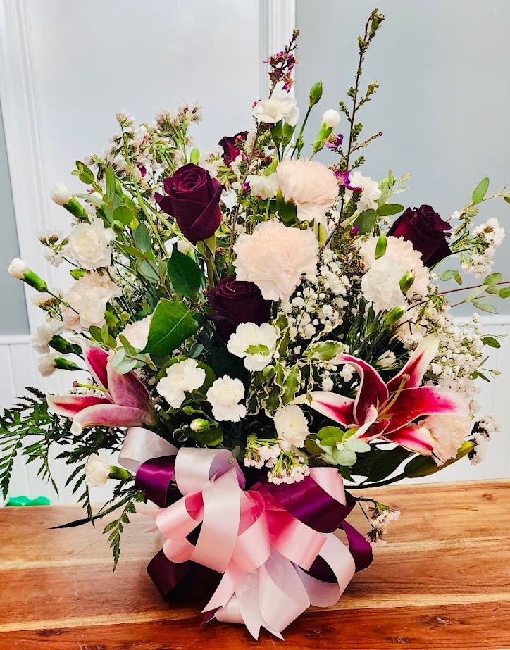 Passion In Purple  - Deep red/puple Roses and Stargaser Lillies with white carnations in a basket with a multi-colored bow.