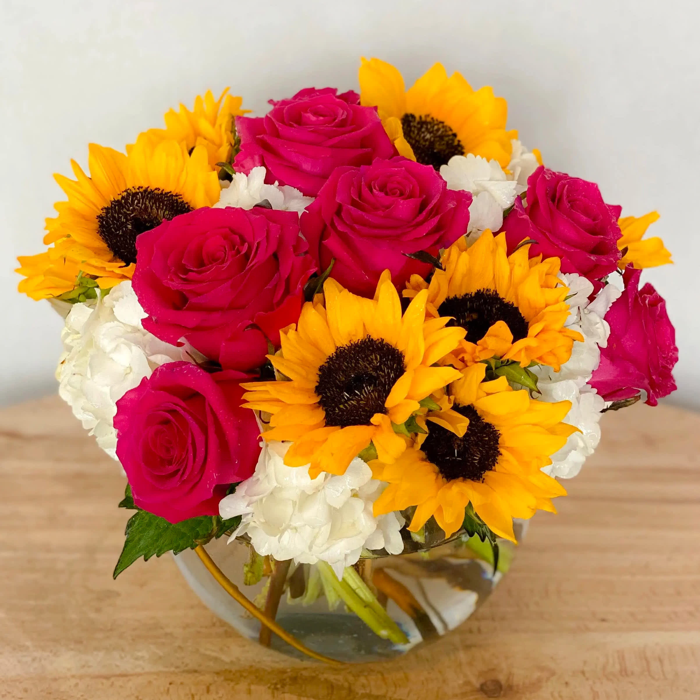 Pinks And Sunflowers  - Precious pink roses and exotic sunflowers designed on a bed of luscious white hydrangea arranged in a keepsake glass bubble vase! Don’t be fooled by my fine description, just take a quick glimpse of this beautiful bouquet and be mesmerized! I’m feeling spring and summer but this is all good for winter and fall... Great all year round! Perfect gift for all occasions and situations! Guaranteed to “Entice”!  Approximately 11” D