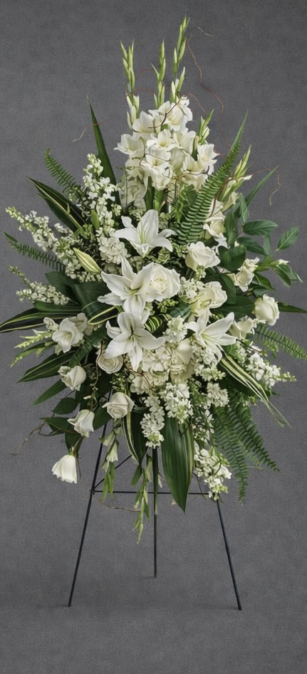 Serene Meadow Standing Spray - This stunning white easel is the perfect way to pay tribute to a loved one. Perfectly adorned with  white and greenery, this piece is sure to add a touching touch of beauty and elegance to any memorial service or sympathy event. The easel stands tall and proud, creating a tasteful and beautiful way to remember a beloved family member.