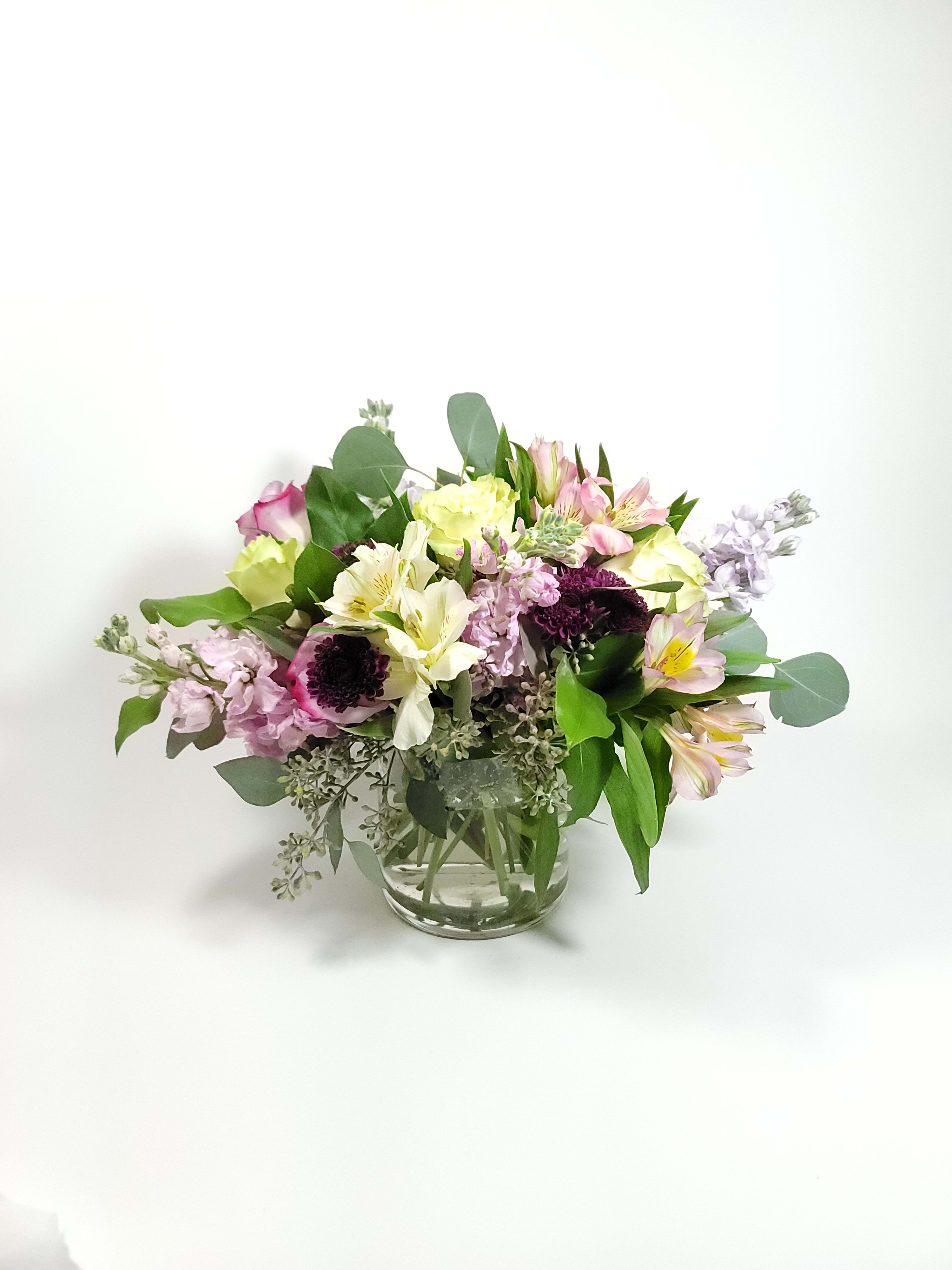 From the Garden - Mixed vintage floral arrangement in a vase with roses, alstroemerias, eucalyptus,  carnations, and seeded eucalyptus. The flowers are soft colors keeping the arrangement loose and airy.