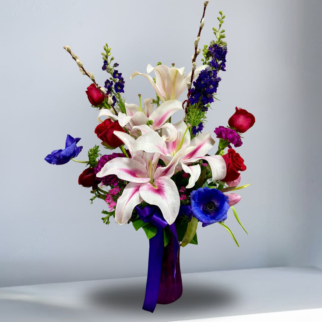 All My Love - Recipe: Seasonal Anenomes, Stargazers, Larkspur, Roses, Tulips, Carnations, DIanthus, and Pussy Willow in a tall vase with purple ribbon.  Seasonal: Seasonal Anenomes Photo shown: Standard