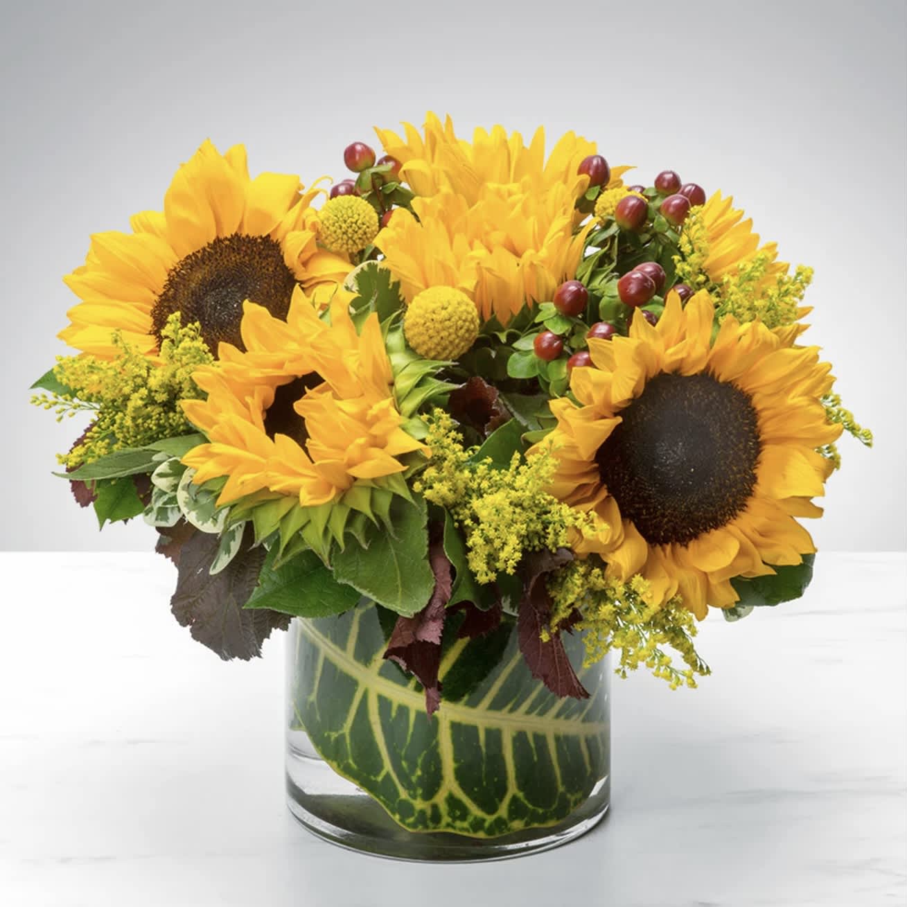 Sunny Sunflowers  - The sun may be pretty great, but sunflowers are the greatest! Fact is, the sun keeps us warm, (we’ll admit it), but sunflowers will never make us sweat! The sun gives us the daytime (which we appreciate), but sunflowers stay more than 12 hours each time! Finally, the sun gives everyone a nice color tan, but sunflowers can never give anyone a sunburn! This autumn, let sunflowers enhance your life, or the life of a loved one, with this Sunny Sunflower arrangement! You will not regret it!  Approximately 9” D