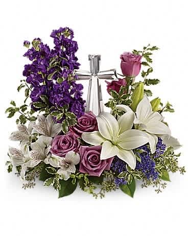 Teleflora's Grace And Majesty Bouquet - A bouquet to remember. This glorious garden of roses, lilies and alstroemeria surrounds a gleaming Crystal Cross. It's a radiant, reverent expression of faith that will be appreciated for years to come. Lavender roses, white asiatic lilies, white alstroemeria, purple stock and purple seafoam statice are arranged with fresh pitta negra, seeded eucalyptus and lemon leaf. Delivered with a Crystal Cross keepsake.