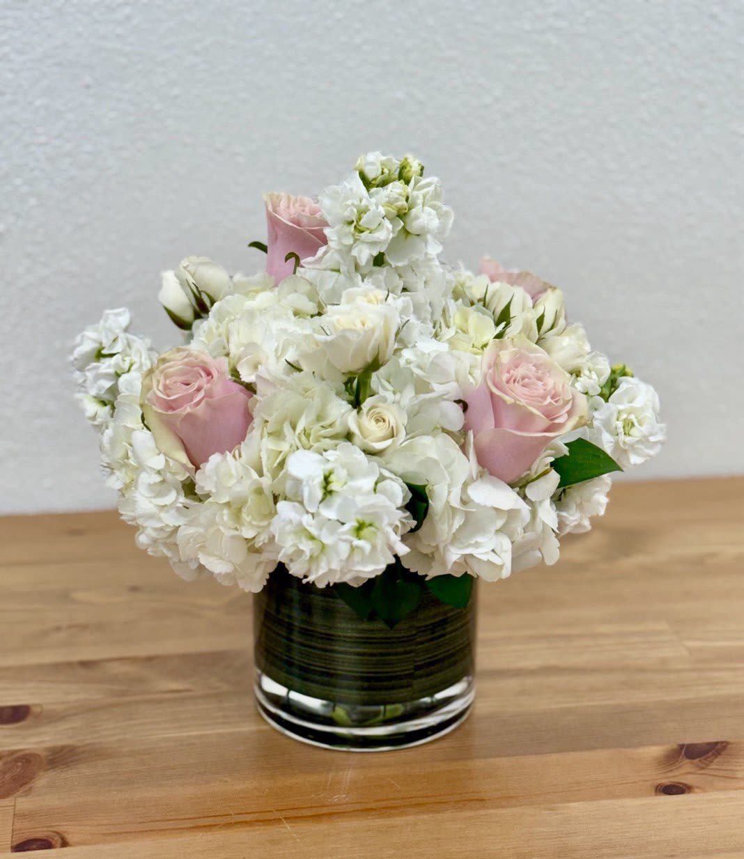 Paint Me Pink - Gorgeous flower arrangement made in a cylinder vase, a fabulous way to celebrate any occasion This beautiful vase is arranged with white hydrangea, white stocks, pink roses, and white spray roses.