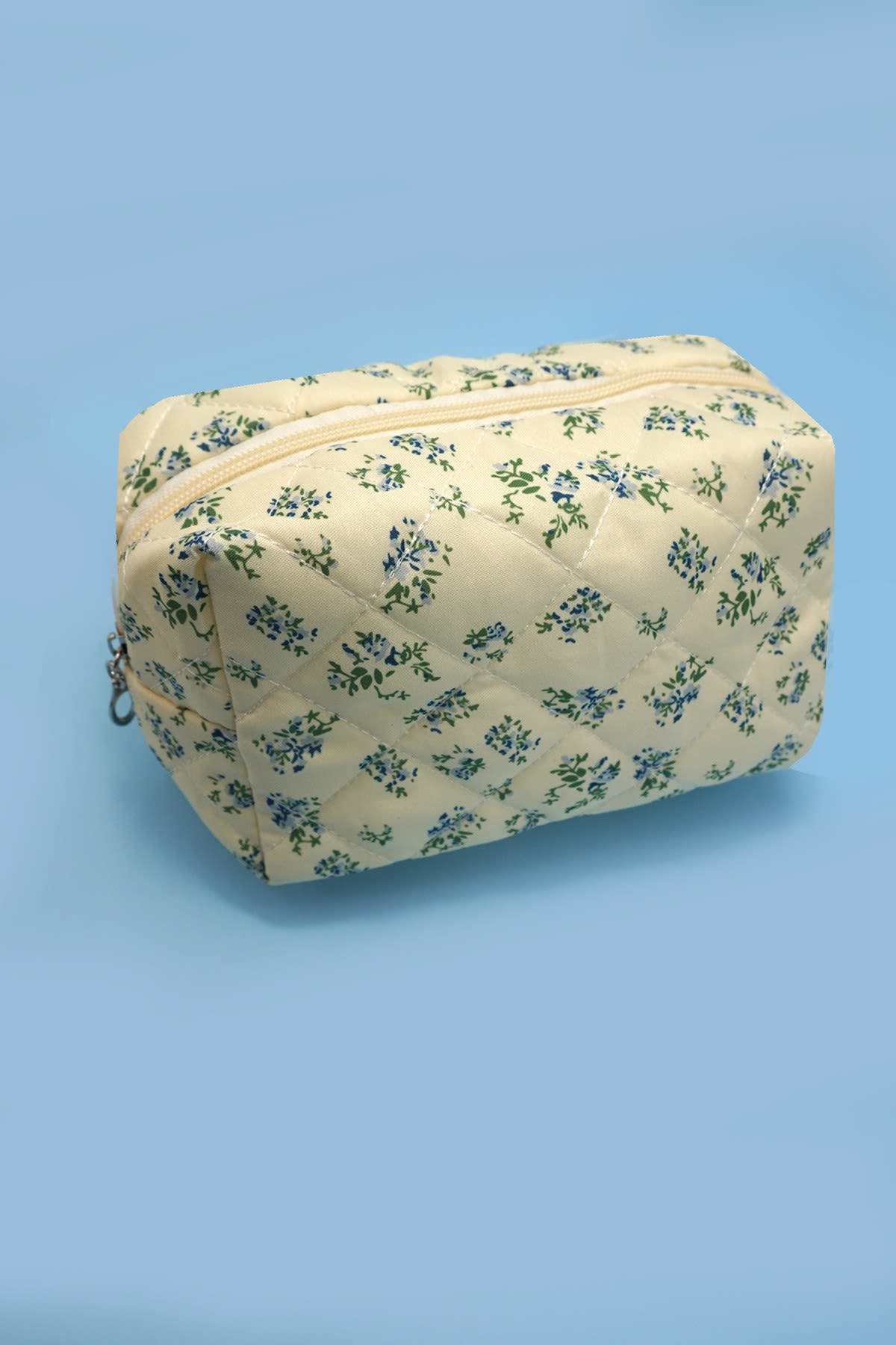 Quilted Blue Floral Cosmetic Bag - A delightful blend of functionality and charm designed to elevate your makeup storage. It offers ample space to organize your cosmetics, brushes, and beauty essentials. Whether you're traveling or simply organizing your vanity, this pouch is perfect for keeping your makeup items secure and easily accessible.   Item Description: Length: 7" height: 4" depth: 3" Zip closure